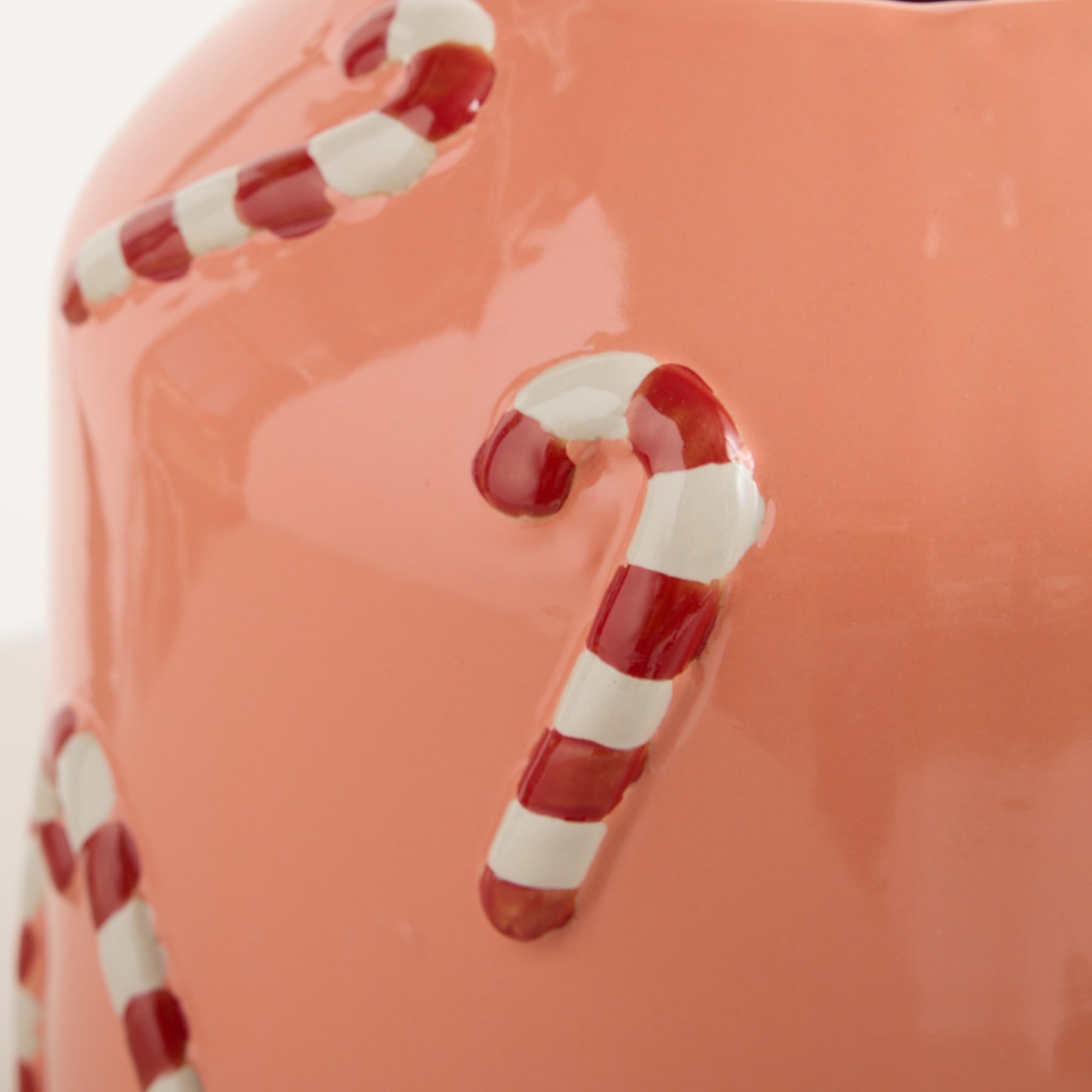 Das Bild zeigt mehrere rot-weiß gestreifte Zuckerstangen vor einem rosa Hintergrund.