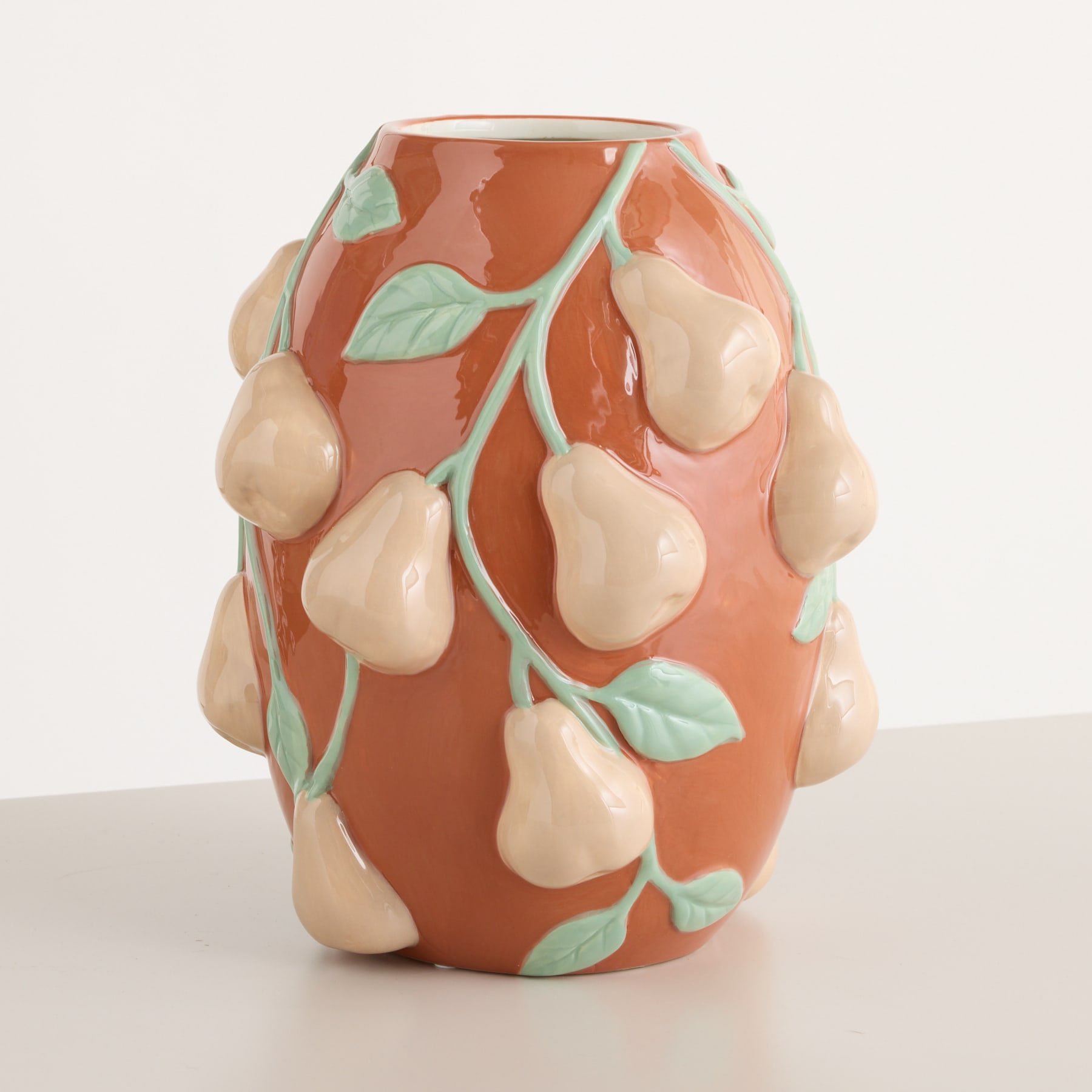 Eine Keramikvase mit leuchtend orangefarbenem Hintergrund und birnenförmigen Designs in verschiedenen Beige- und Grüntönen, die eine optisch beeindruckende und organische Komposition ergeben.