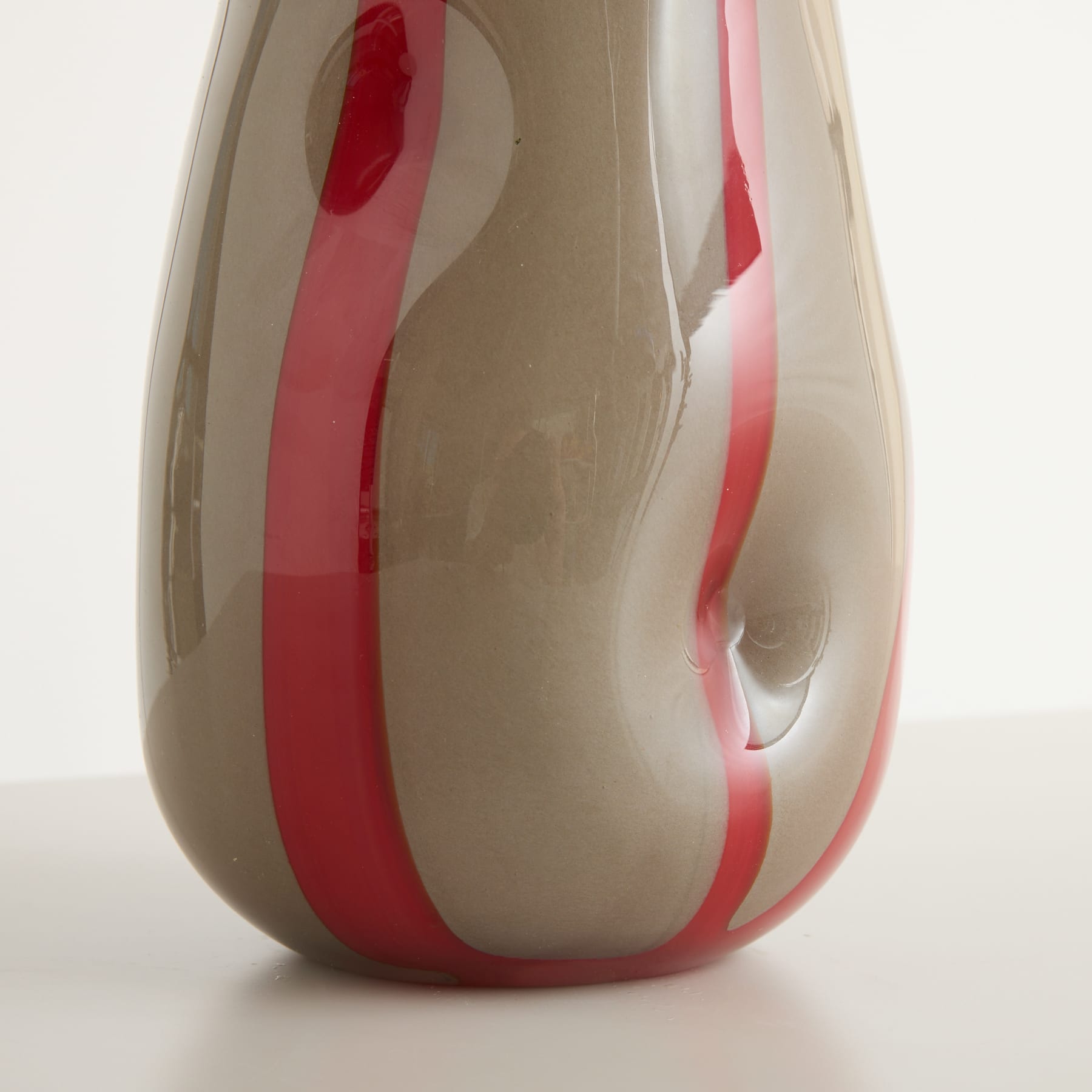 Eine Glasvase in Beige und Rosa mit deutlichen Wirbelmustern, die ein optisch auffälliges und abstraktes Design erzeugen.