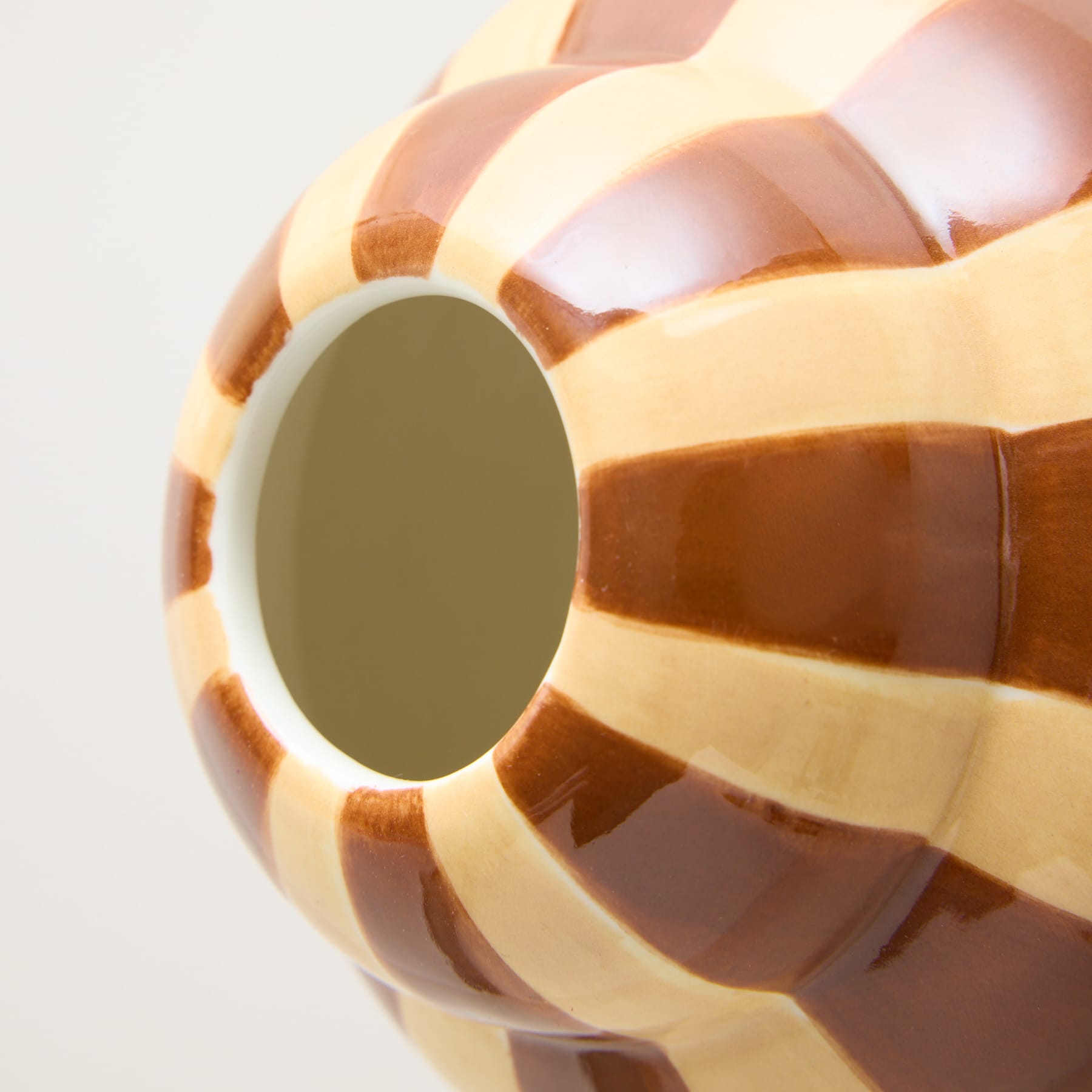Eine Nahaufnahme eines runden, mehrfarbigen Desserts mit einer spiegelähnlichen Oberfläche in der Mitte vor einem schlichten weißen Hintergrund.
