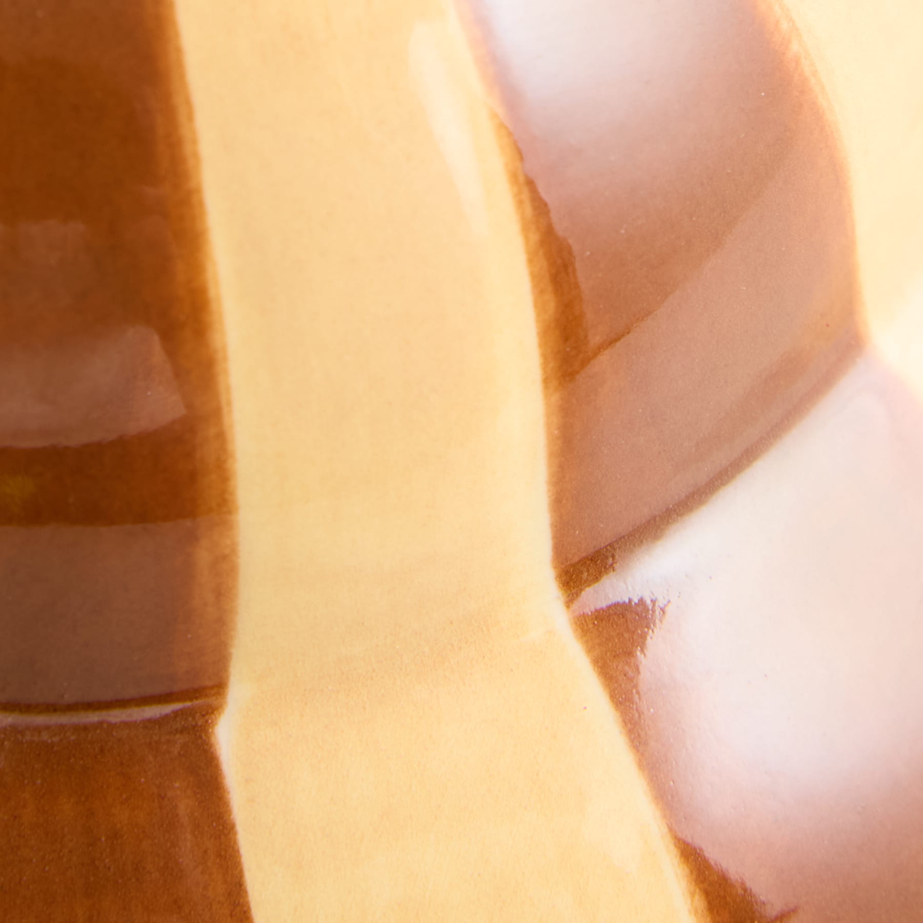Das Bild zeigt eine Nahaufnahme einer Glasflasche oder eines Glasbehälters, wobei der Vordergrund von der gekrümmten, durchscheinenden Oberfläche dominiert wird und der Hintergrund unscharf und unscharf erscheint.