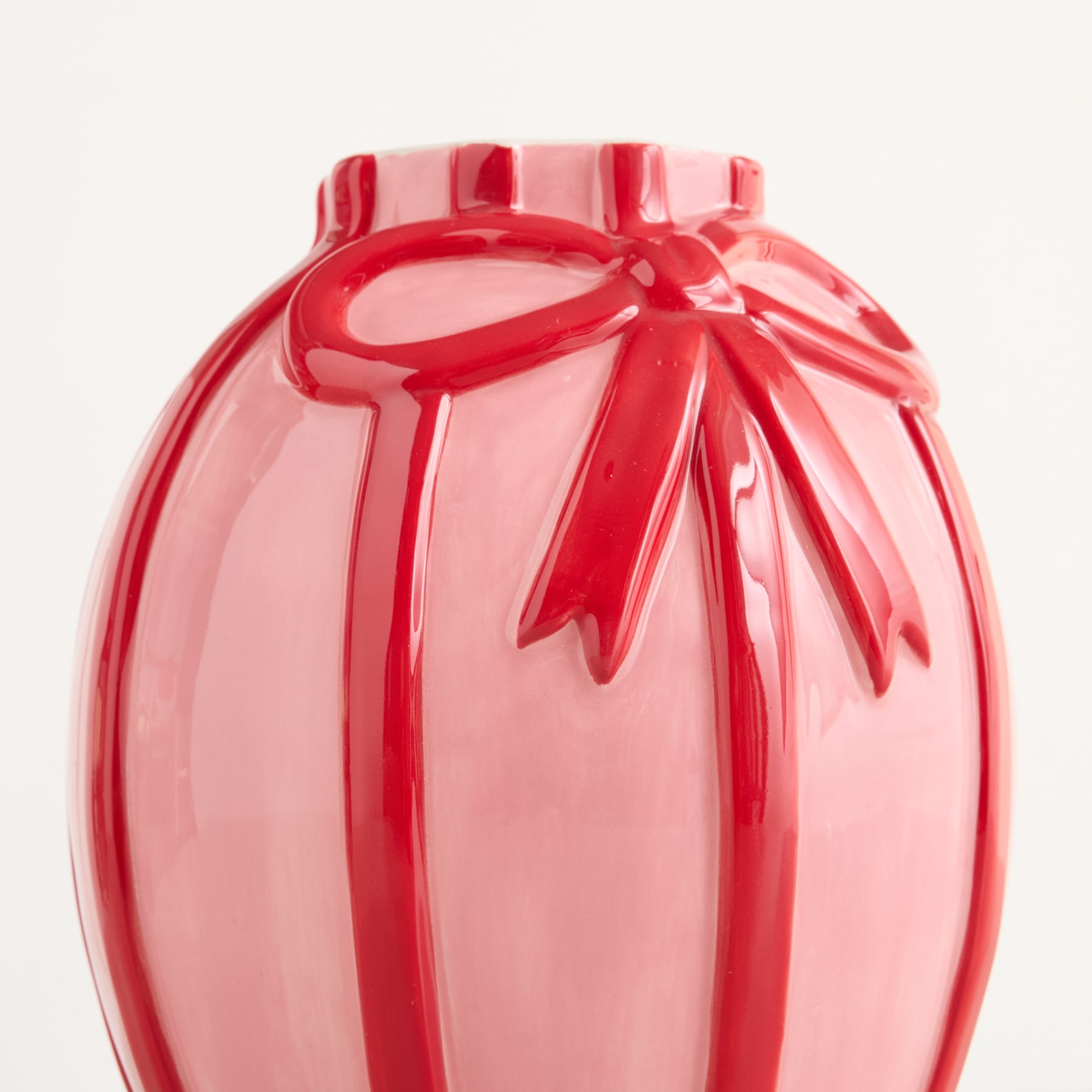 Eine leuchtend rote Glasvase mit einem unverwechselbaren Blumenmuster steht vor einem schlichten weißen Hintergrund.