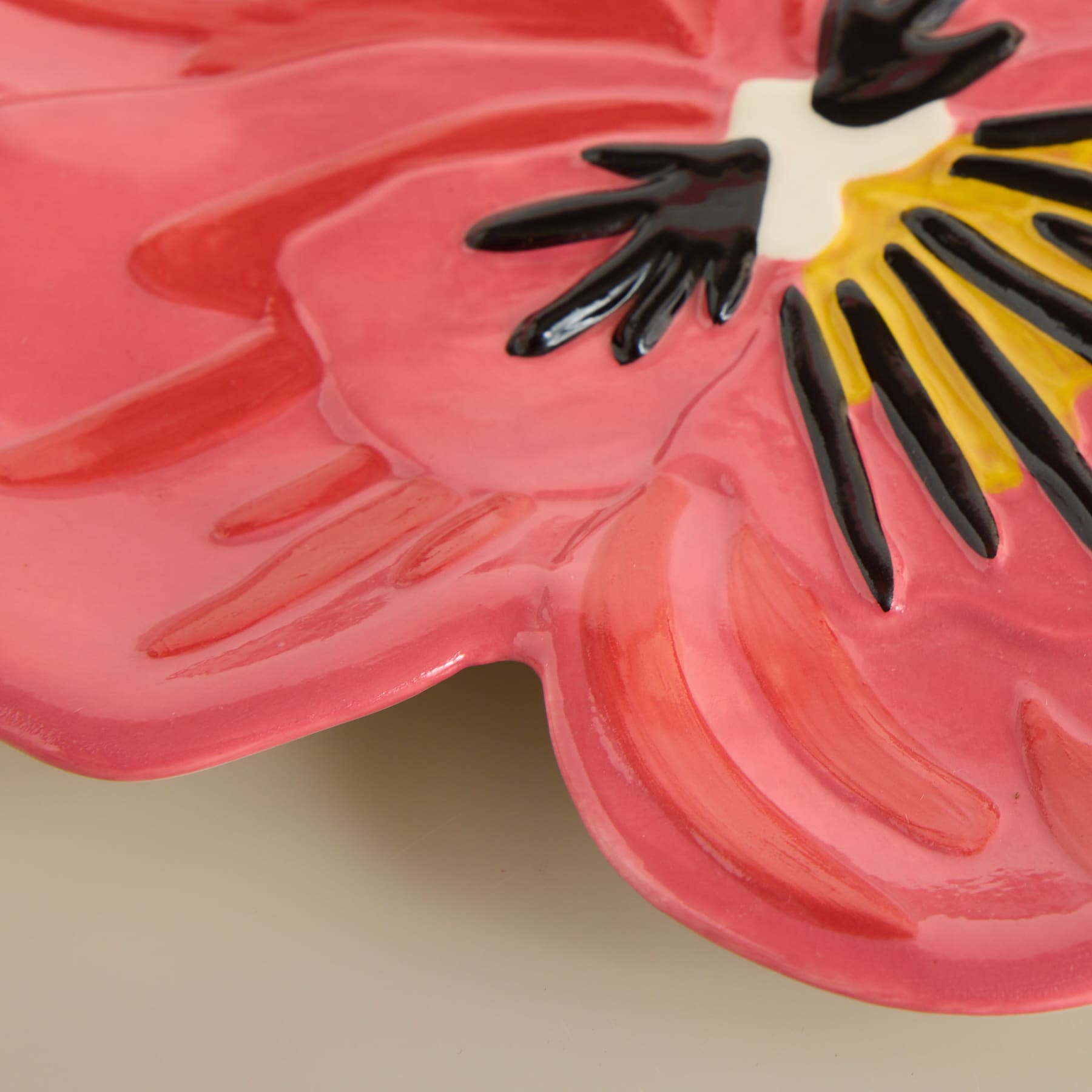 Ein lebendiges, abstraktes Blumendesign mit kräftigen, überlappenden Blütenblättern in Rot- und Gelbtönen vor einem weichen, neutralen Hintergrund.