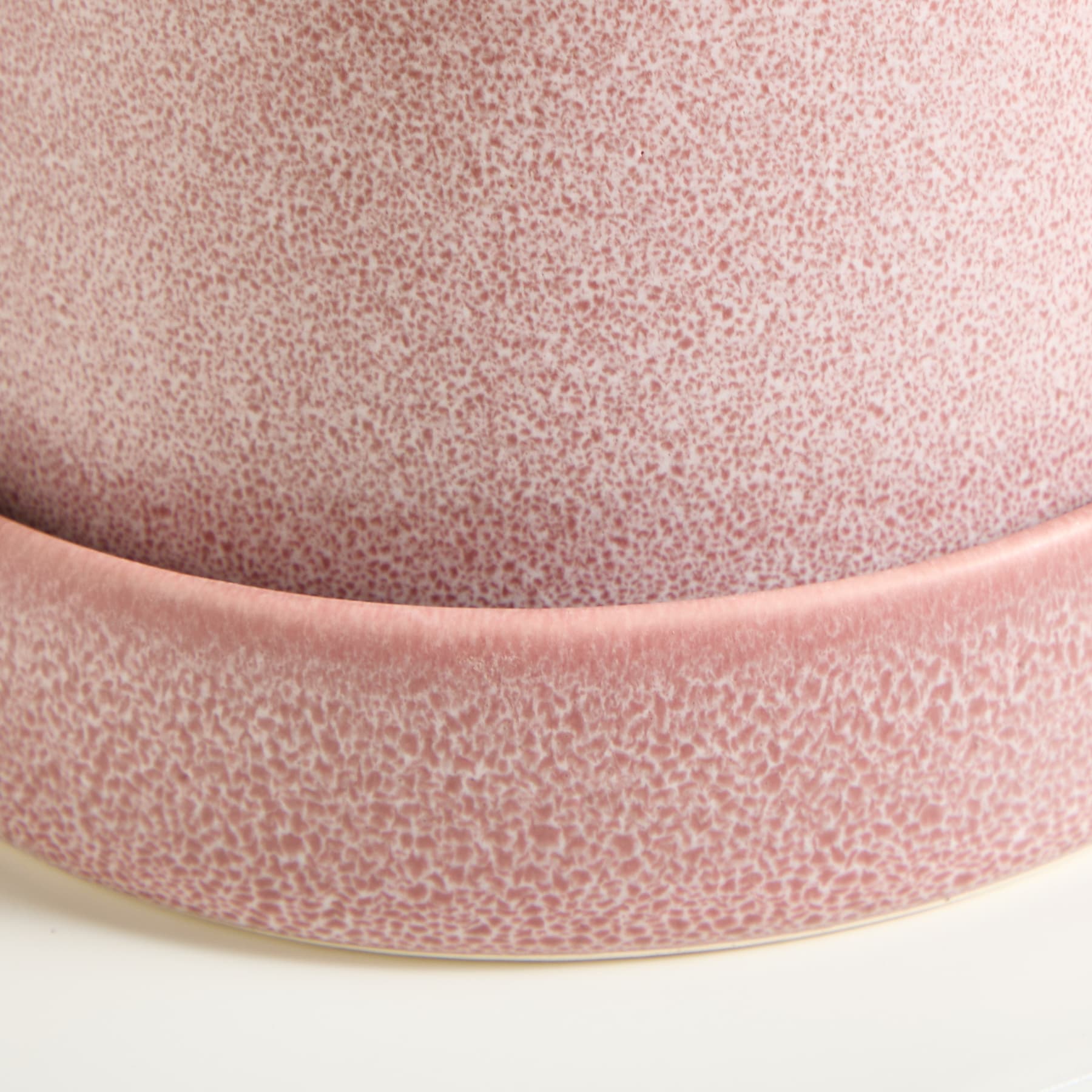 Eine Nahaufnahme einer rosa Keramikschale mit strukturierter, gesprenkelter Oberfläche vor einem schlichten weißen Hintergrund.