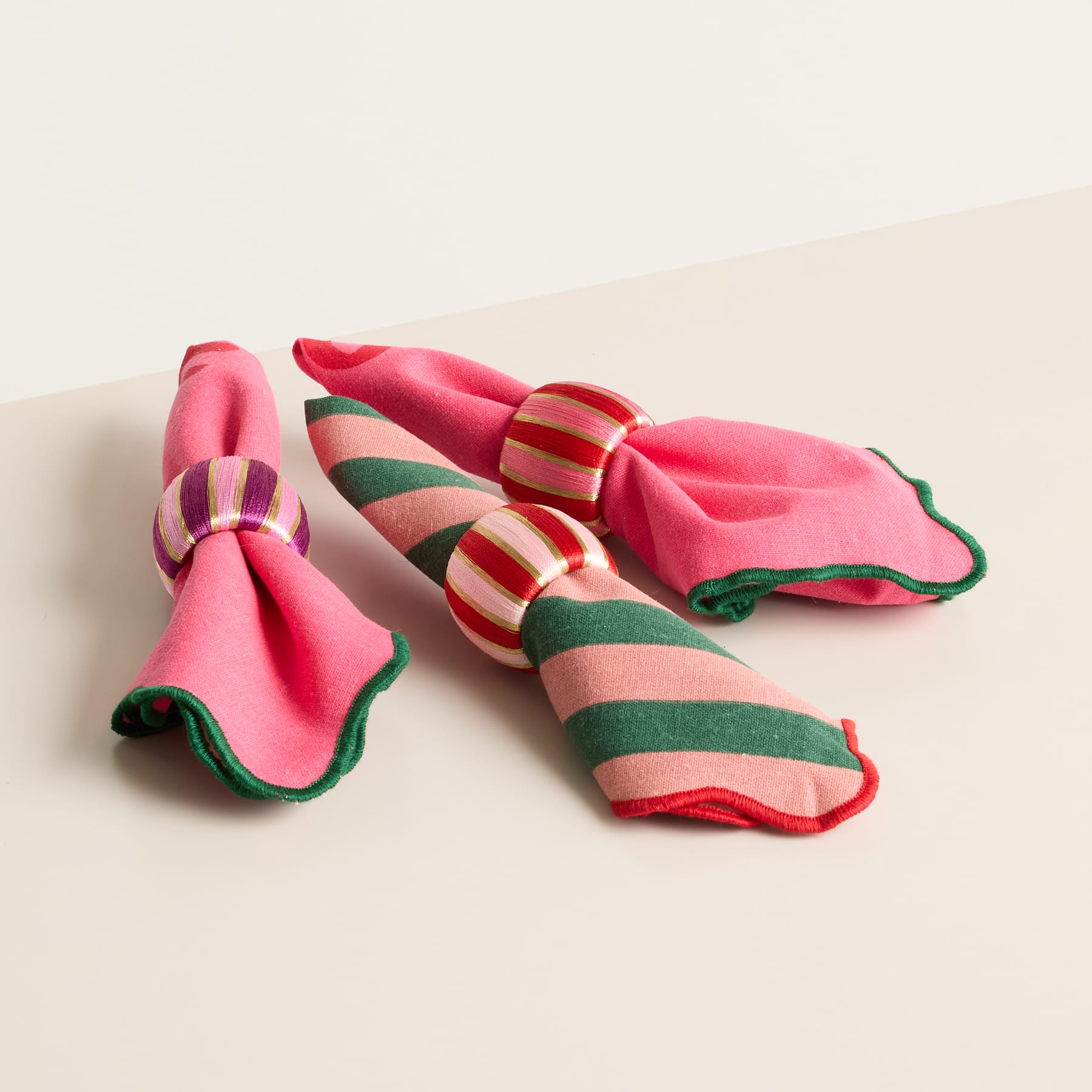 Das Bild zeigt ein Paar rosa und grün gestreifte Socken oder Hausschuhe auf einer hellen Oberfläche.