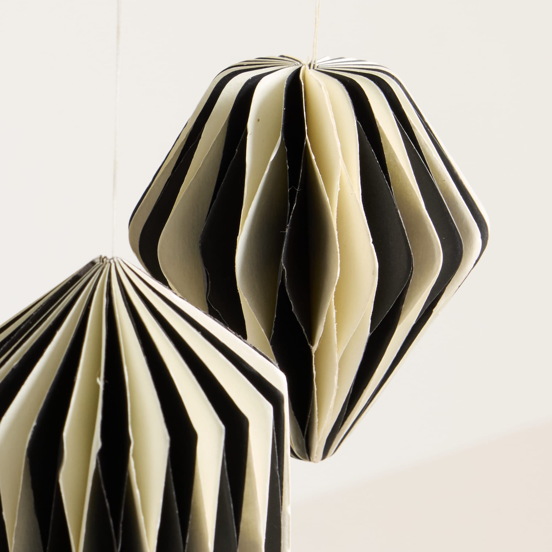 Das Bild zeigt eine markante geometrische Papierskulptur mit abwechselnd schwarzen und weißen Streifen, die vor einem schlichten Hintergrund eine optisch fesselnde und abstrakte Komposition ergibt.