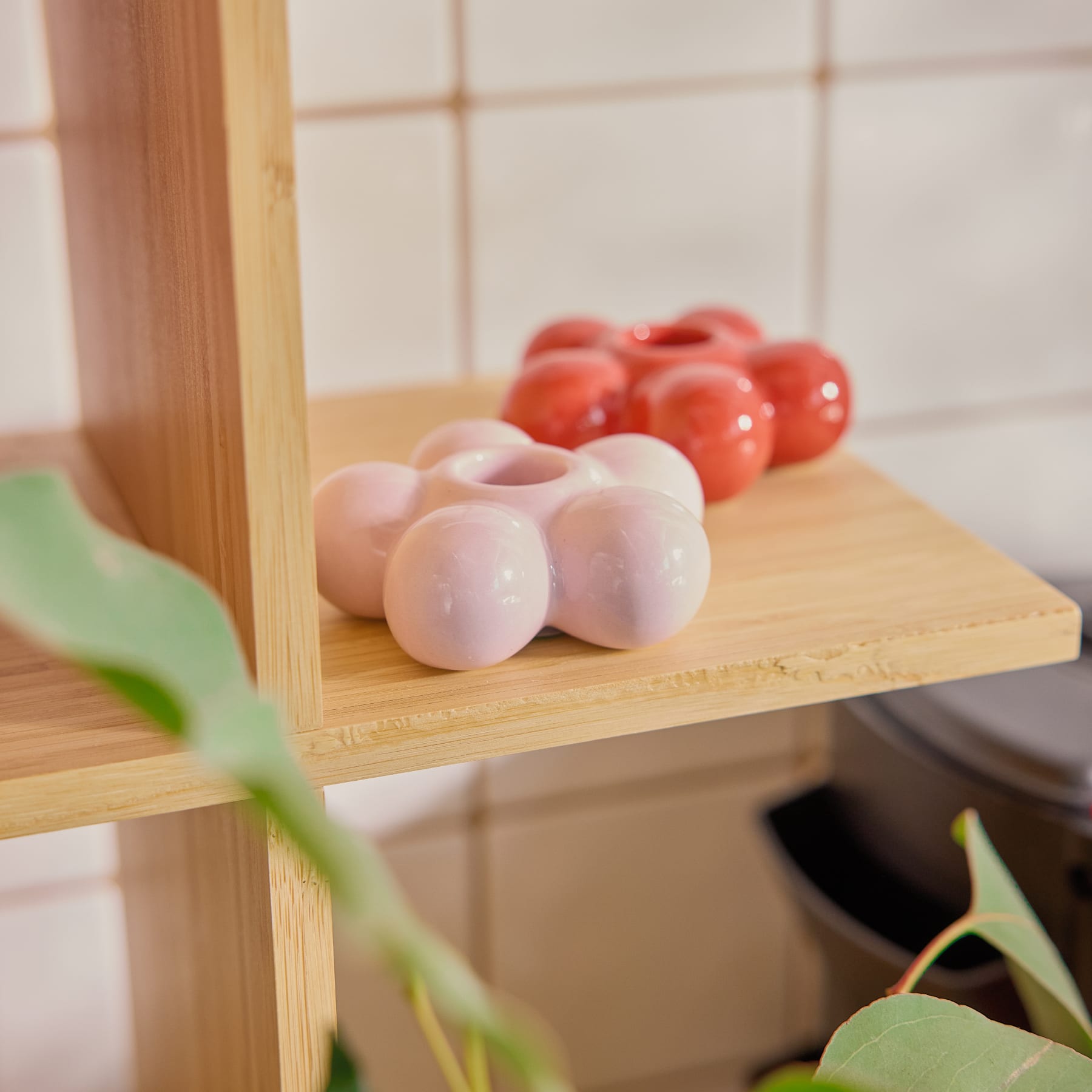 Eine Ansammlung zarter, pastellrosa Kugeln, die in blumenähnlicher Form vor einem schlichten, hellen Hintergrund angeordnet sind.