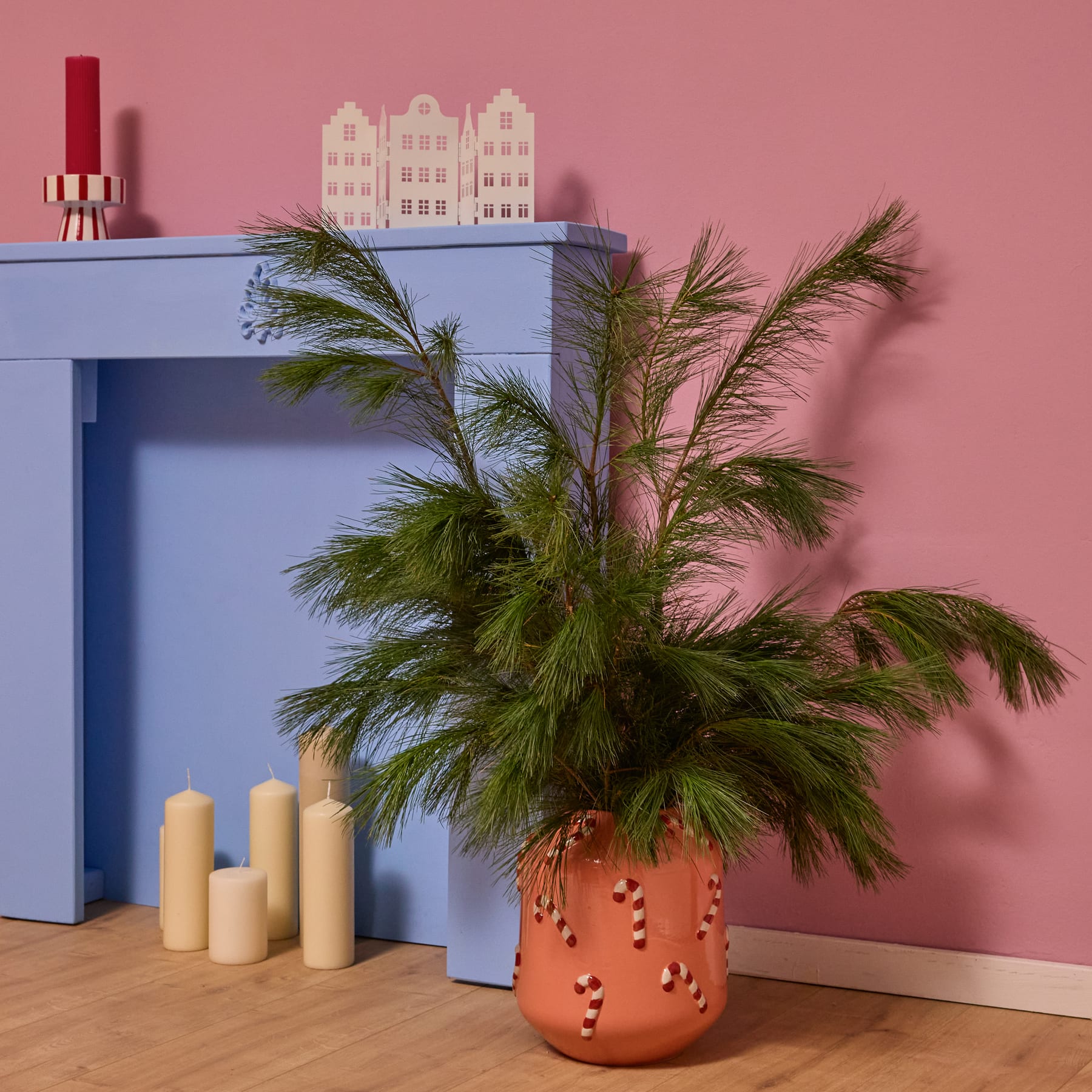 Eine pfirsichfarbene Keramikvase oder ein Behälter mit rot-weißen, zuckerstangenartigen Mustern auf der Oberfläche, vor einem schlichten weißen Hintergrund.