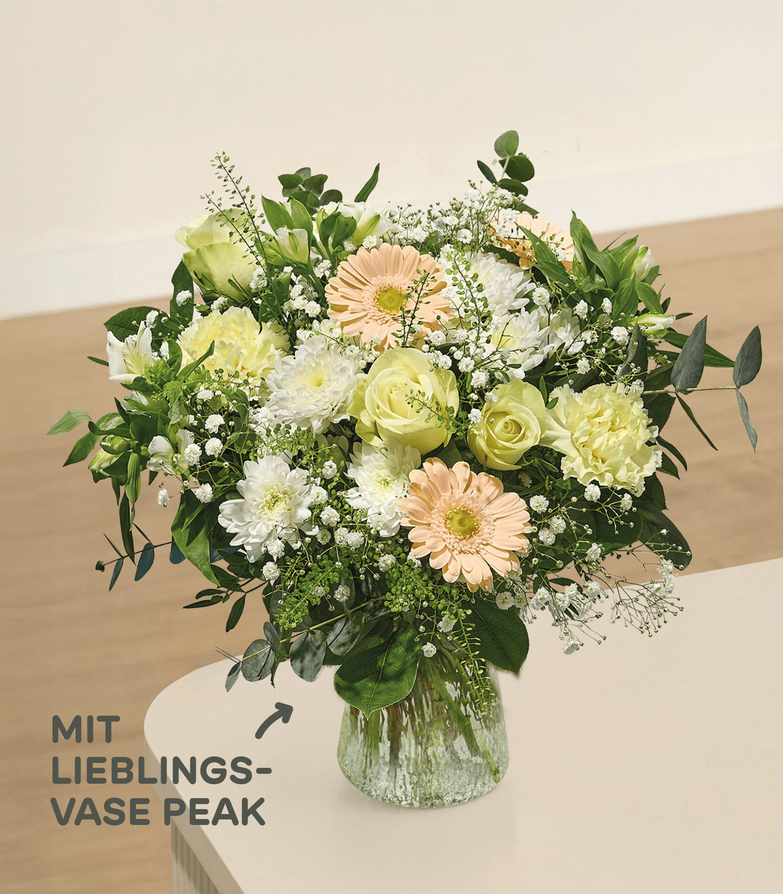 Im Vordergrund füllt ein leuchtender Strauß gelber und rosafarbener Blumen mit Schleierkraut eine strukturierte Glasvase vor einem weichen, verschwommenen Hintergrund.
