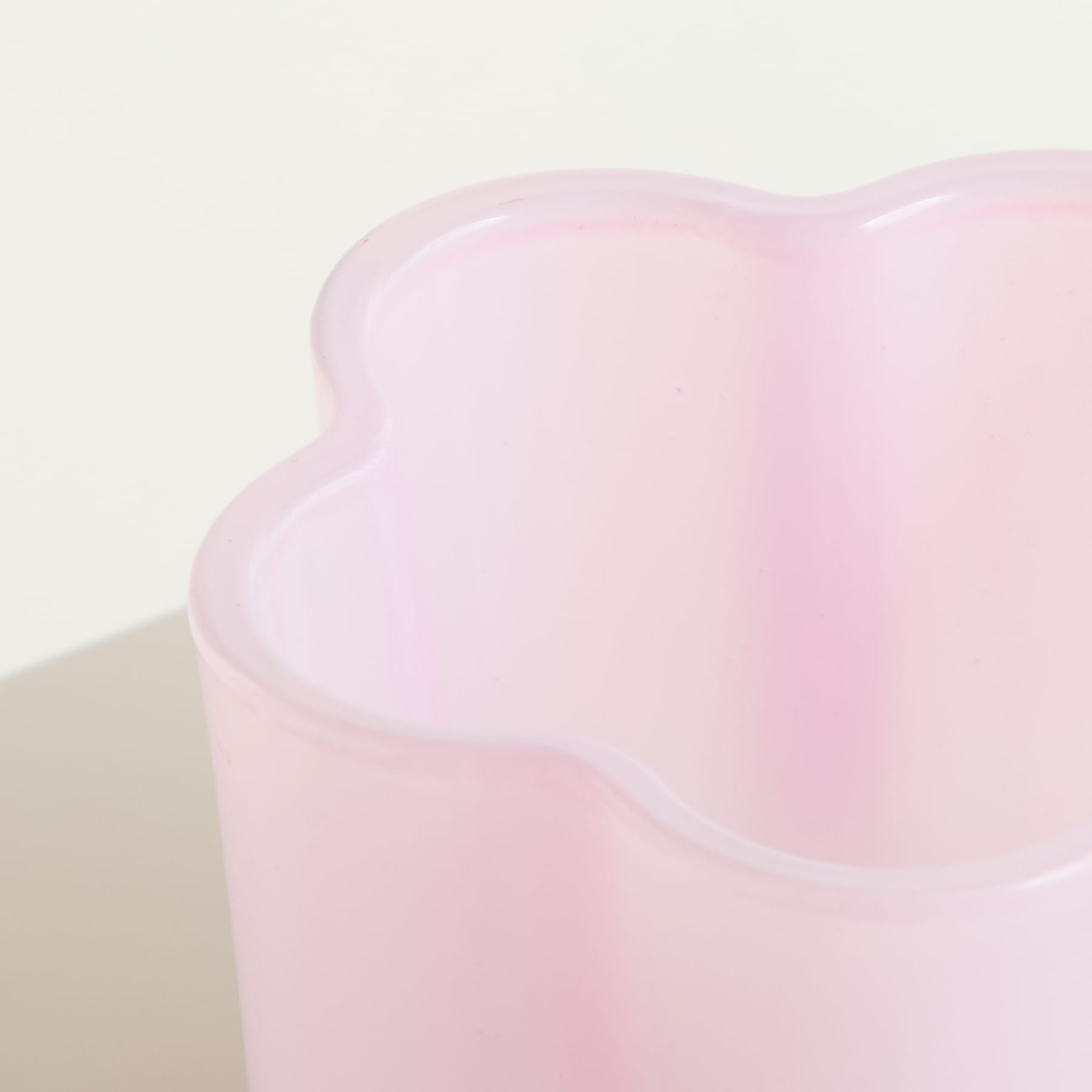 Eine Sammlung farbenfroher, pastellfarbener Glasbecher oder Vasen, die auf einem schlichten Hintergrund angeordnet sind.