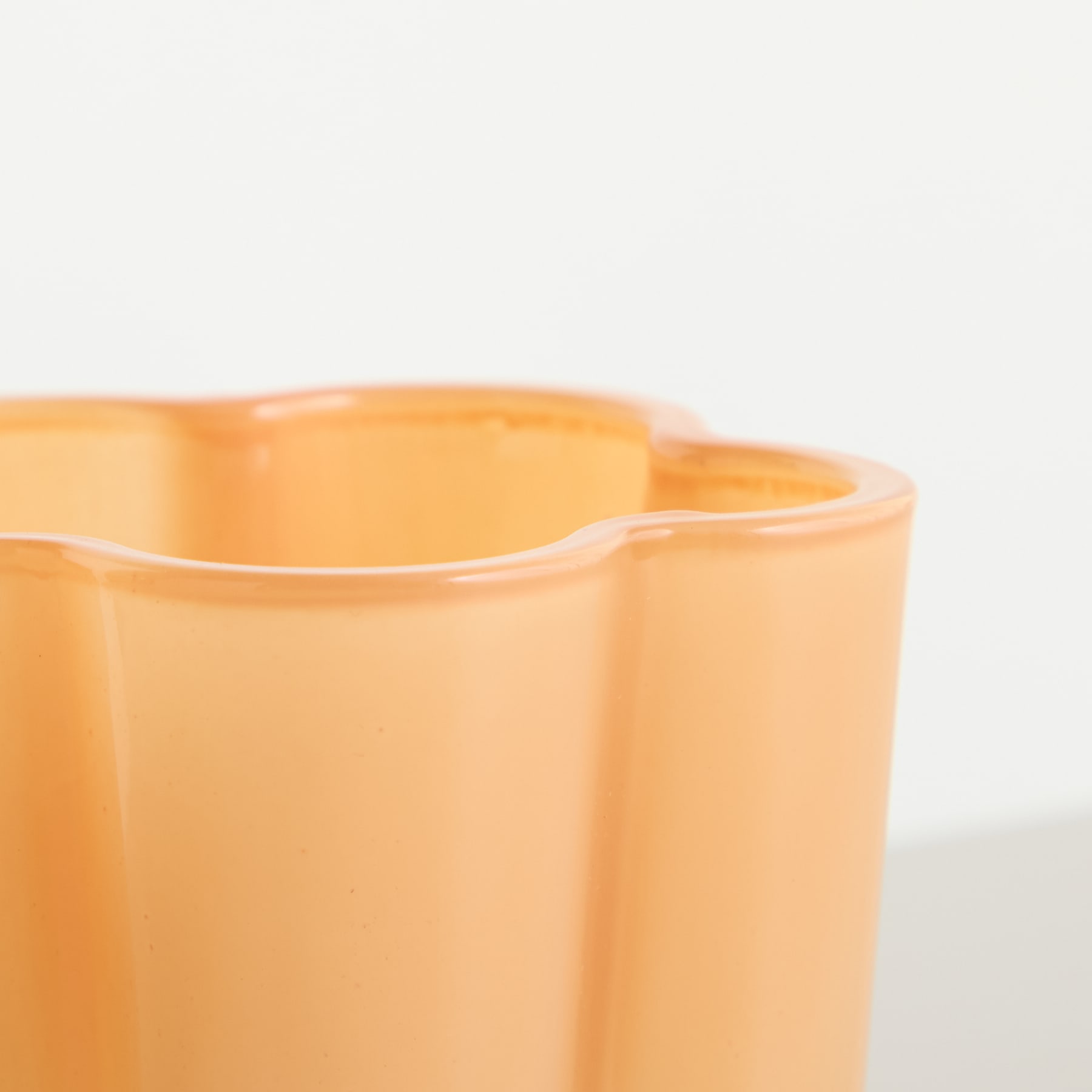 Eine Sammlung farbenfroher, pastellfarbener Glasbecher oder Vasen, die auf einem schlichten Hintergrund angeordnet sind.