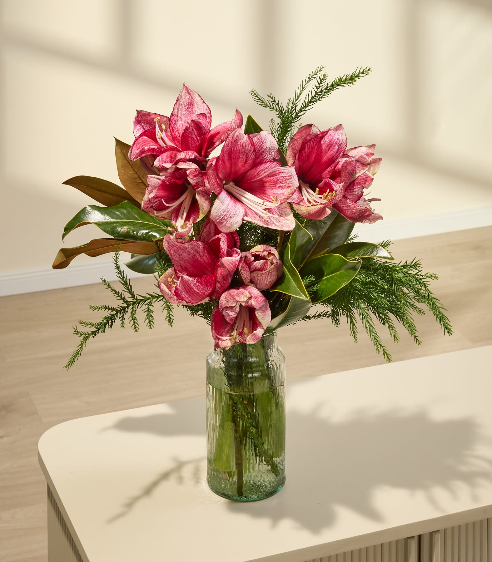 Ein leuchtender Strauß üppiger, rosa Tulpen, den eine Person vor einem schlichten weißen Hintergrund in den Händen hält.