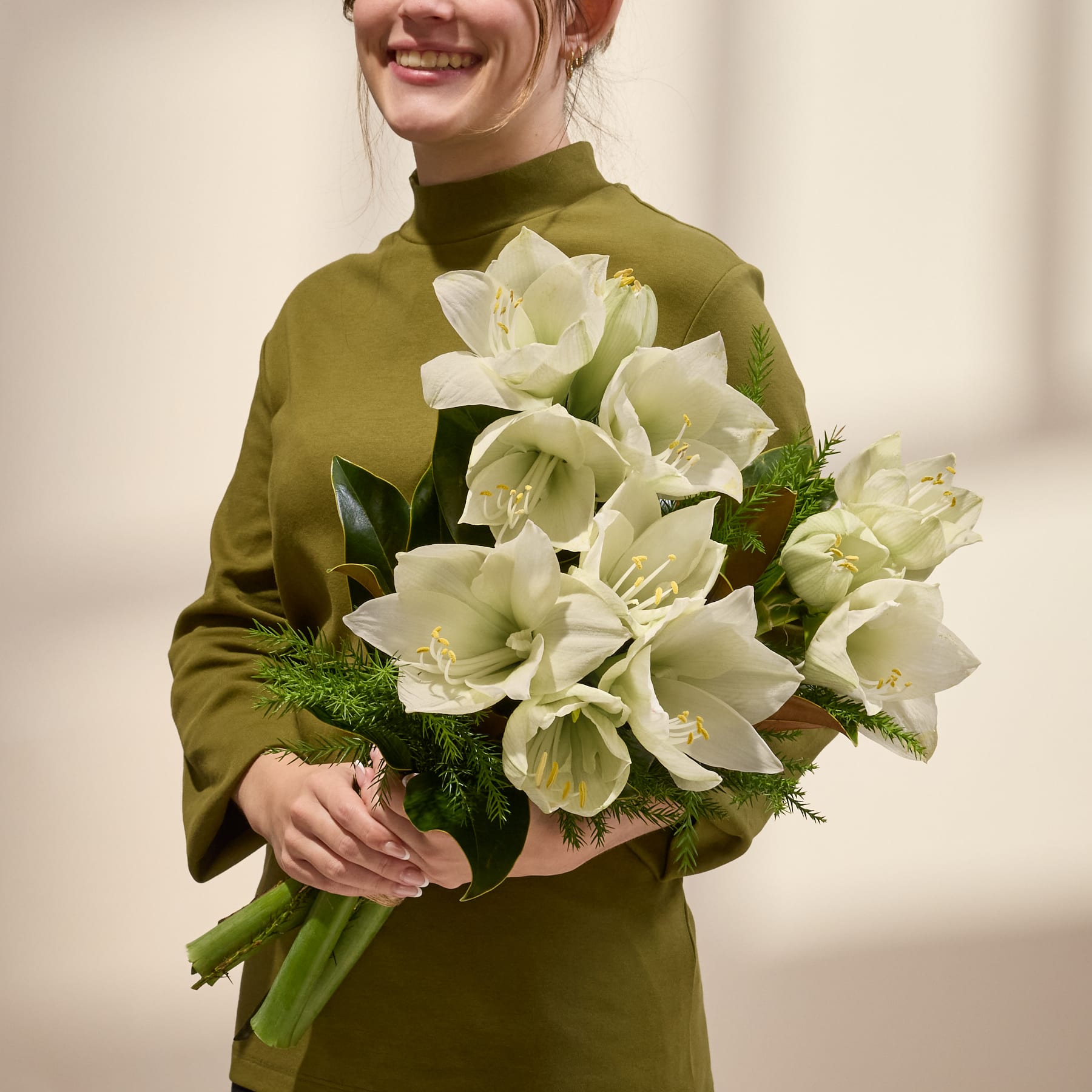 Ein Strauß weißer und gelber Tulpen mit grünen Blättern und Stielen vor einem schlichten weißen Hintergrund.