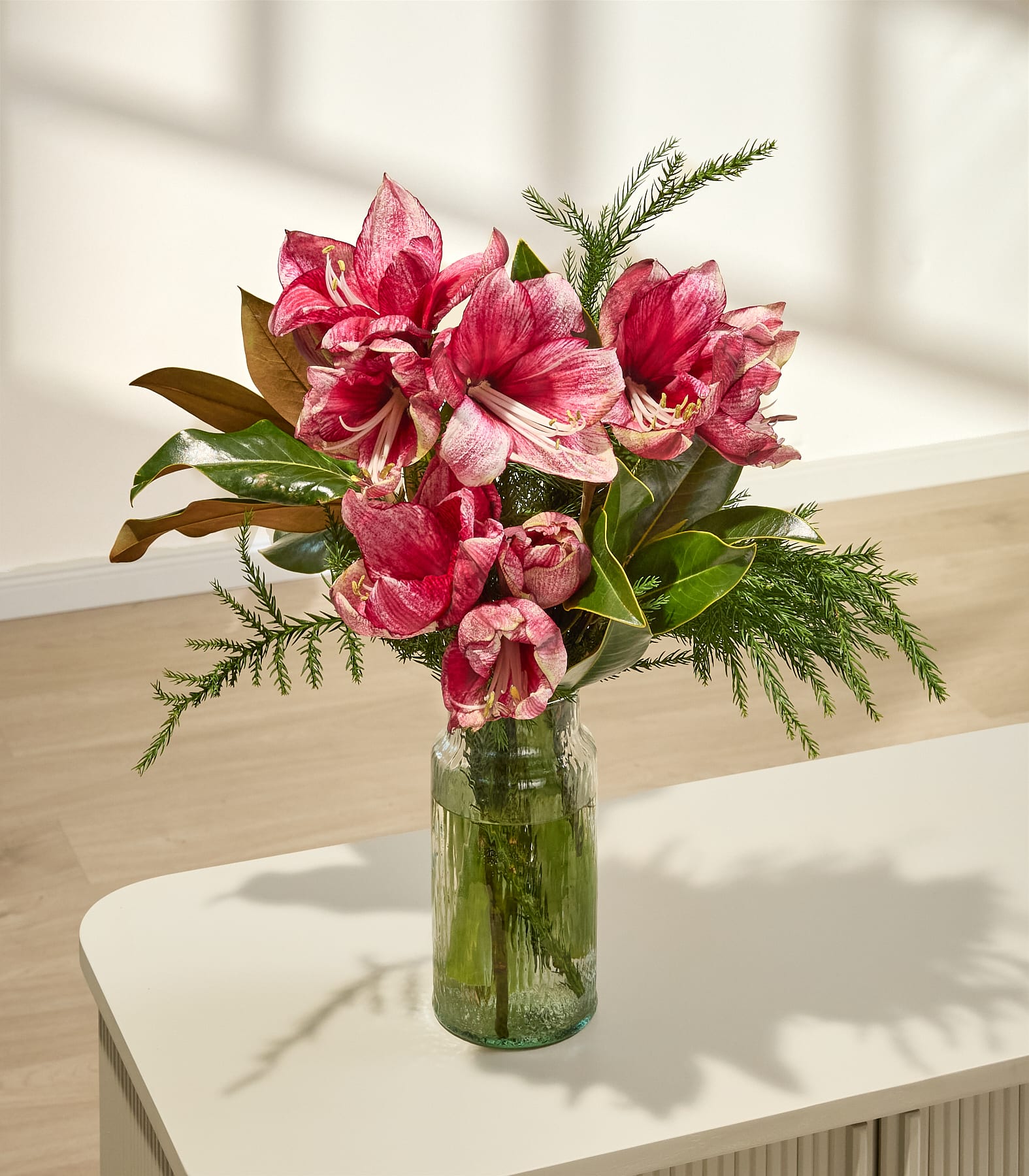 Ein leuchtender Strauß üppiger, rosa Tulpen, den eine Person vor einem schlichten weißen Hintergrund in den Händen hält.