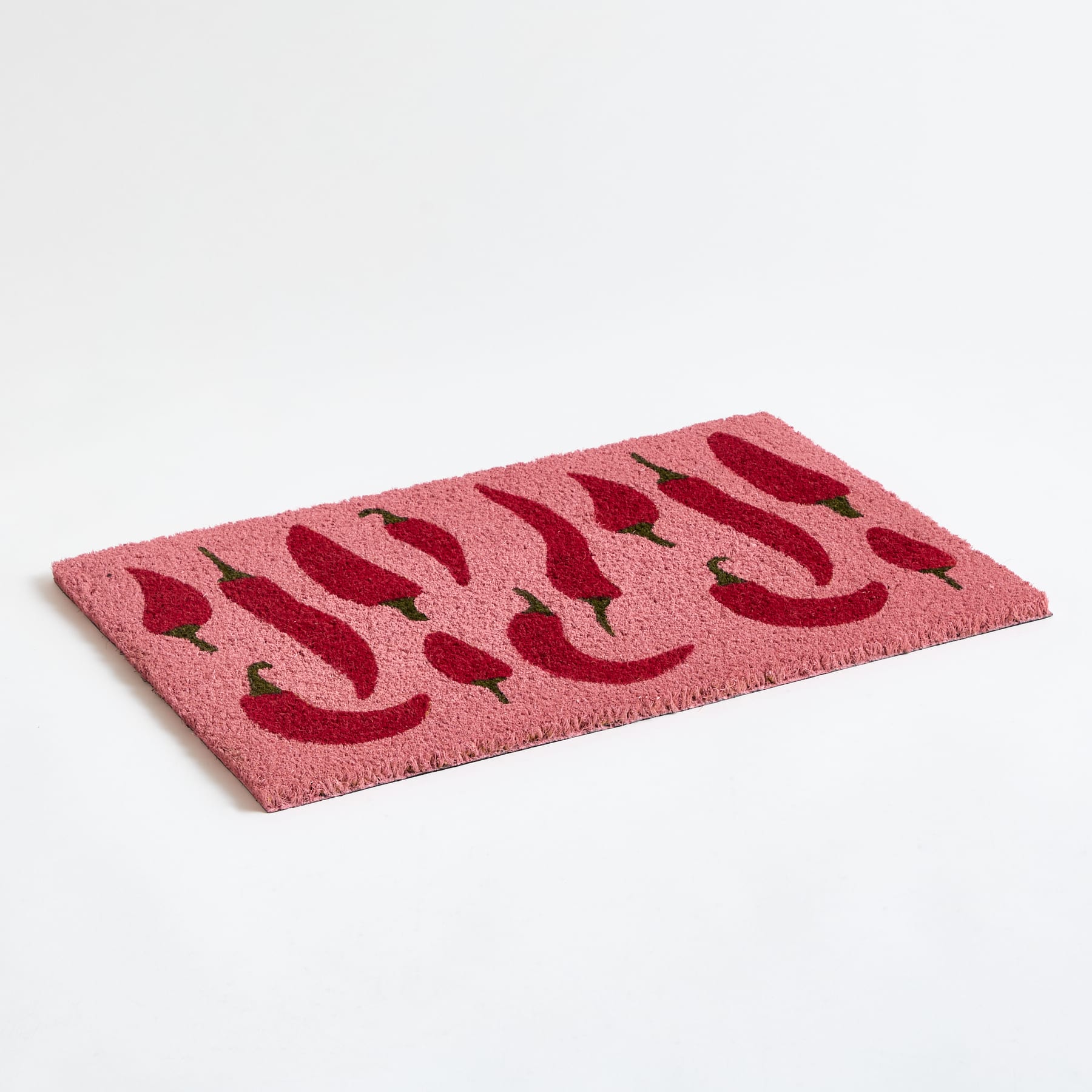 Eine rosa-rot gemusterte Fußmatte oder ein Teppich liegt auf einem schlichten weißen Hintergrund.