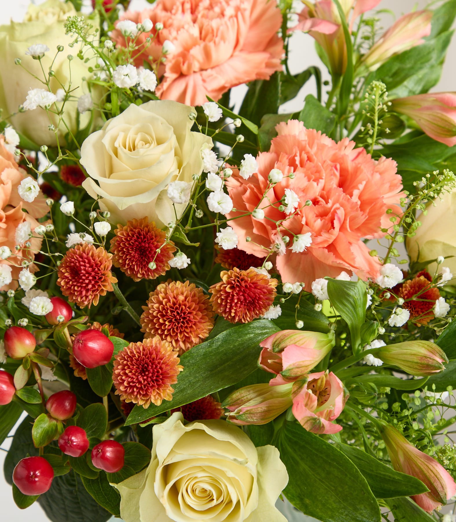 Eine junge Frau mit rotem Haar und einem floralen Haarschmuck hält einen leuchtend bunten Blumenstrauß vor einem schlichten weißen Hintergrund.