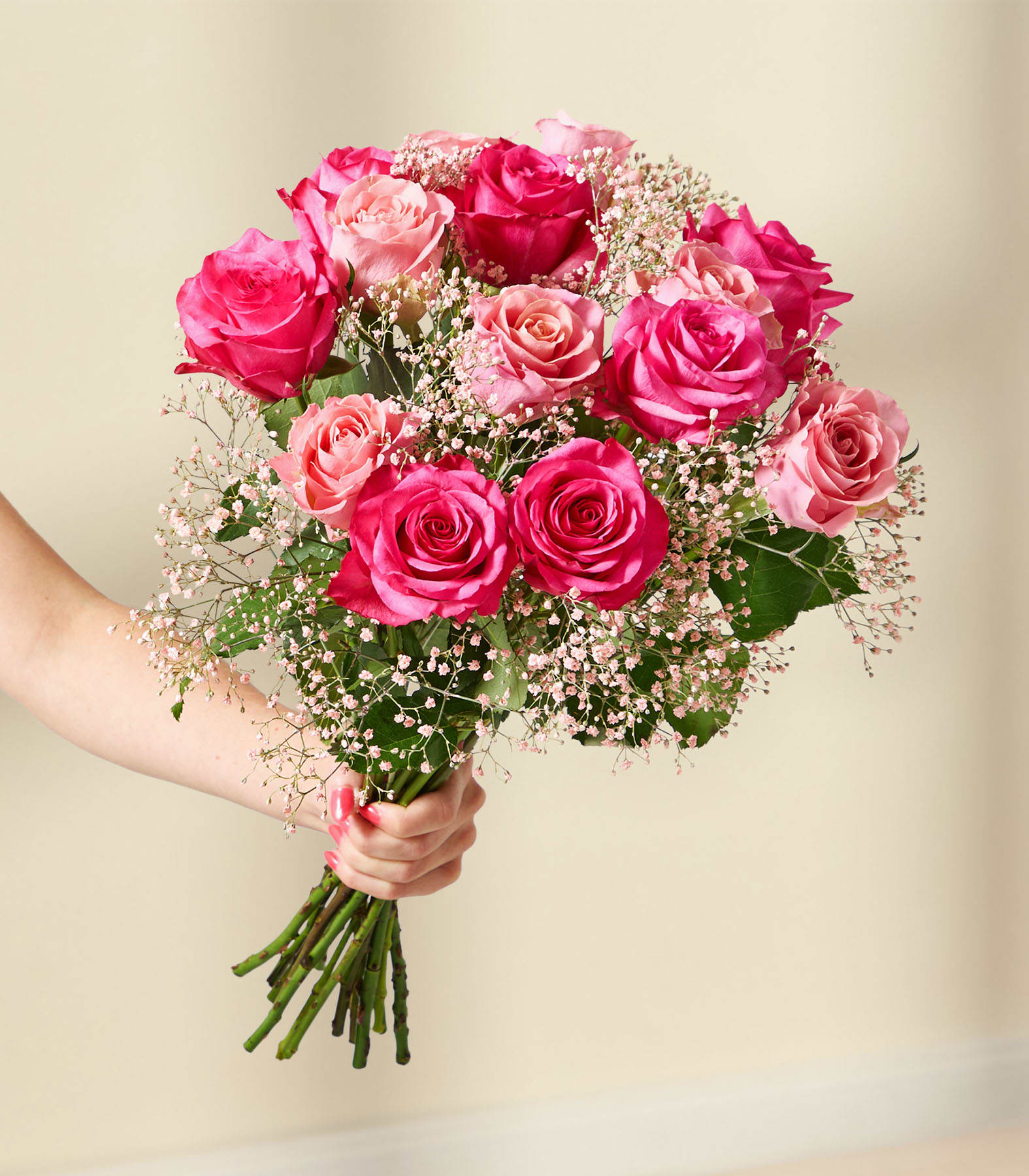 Ein lebendiger Strauß üppiger, samtiger roter und rosafarbener Rosen, umgeben von zarten Schleierkrautblüten, vor einem weichen, verschwommenen Hintergrund.