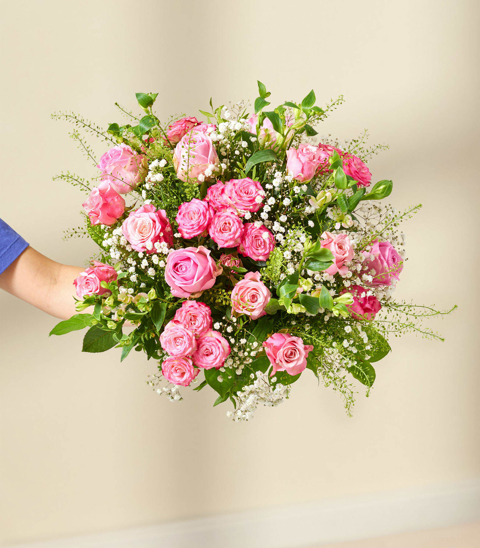 Ein leuchtender Strauß rosa Rosen, umgeben von zarten weißen Blüten und üppigem Grün, ergibt ein optisch atemberaubendes und beruhigendes Blumenarrangement.