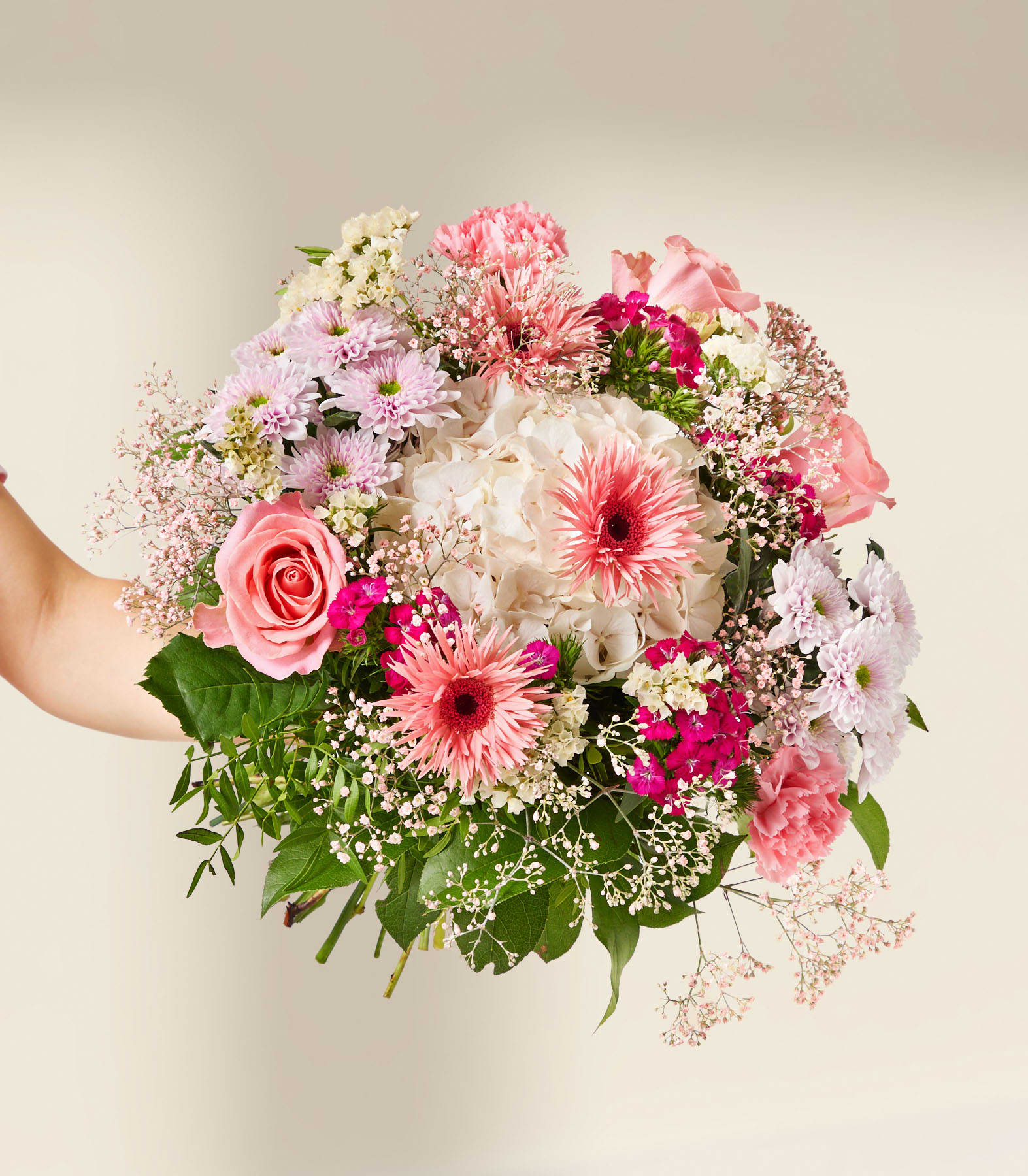 Eine Hand hält einen leuchtenden Strauß rosa und weißer Blumen vor einem sanften, neutralen Hintergrund.