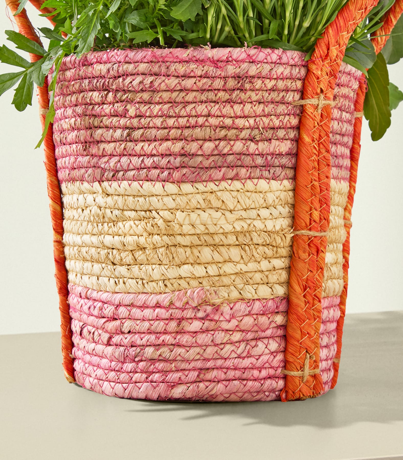 Ein geflochtener Korb gefüllt mit frischen grünen Kräutern und Gemüse, mit einer lebendigen Farbpalette aus Rosa-, Orange- und Beigetönen.