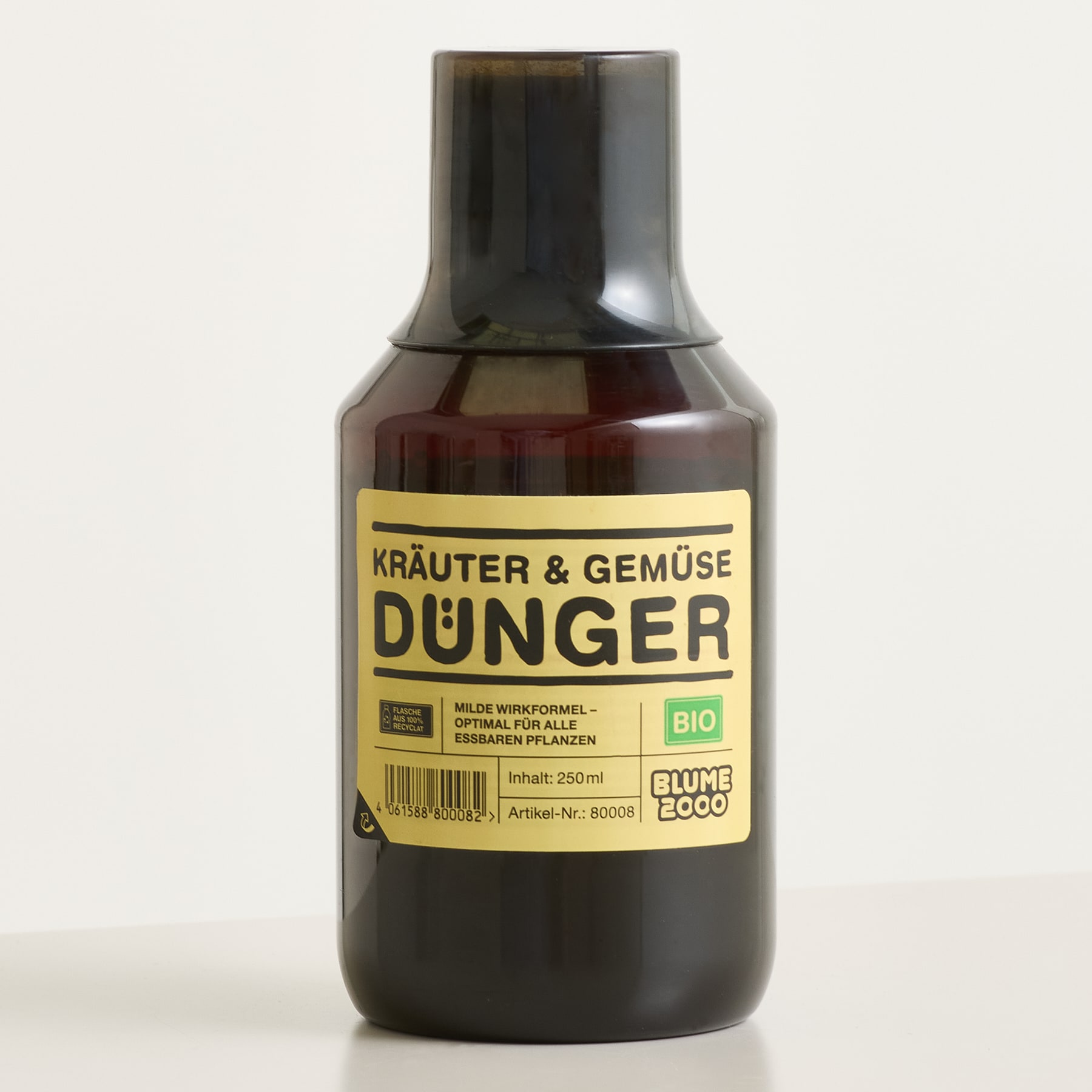 Eine dunkelbraune Flasche mit organischem Dünger für Kräuter und Gemüse steht vor einem schlichten, hellen Hintergrund.