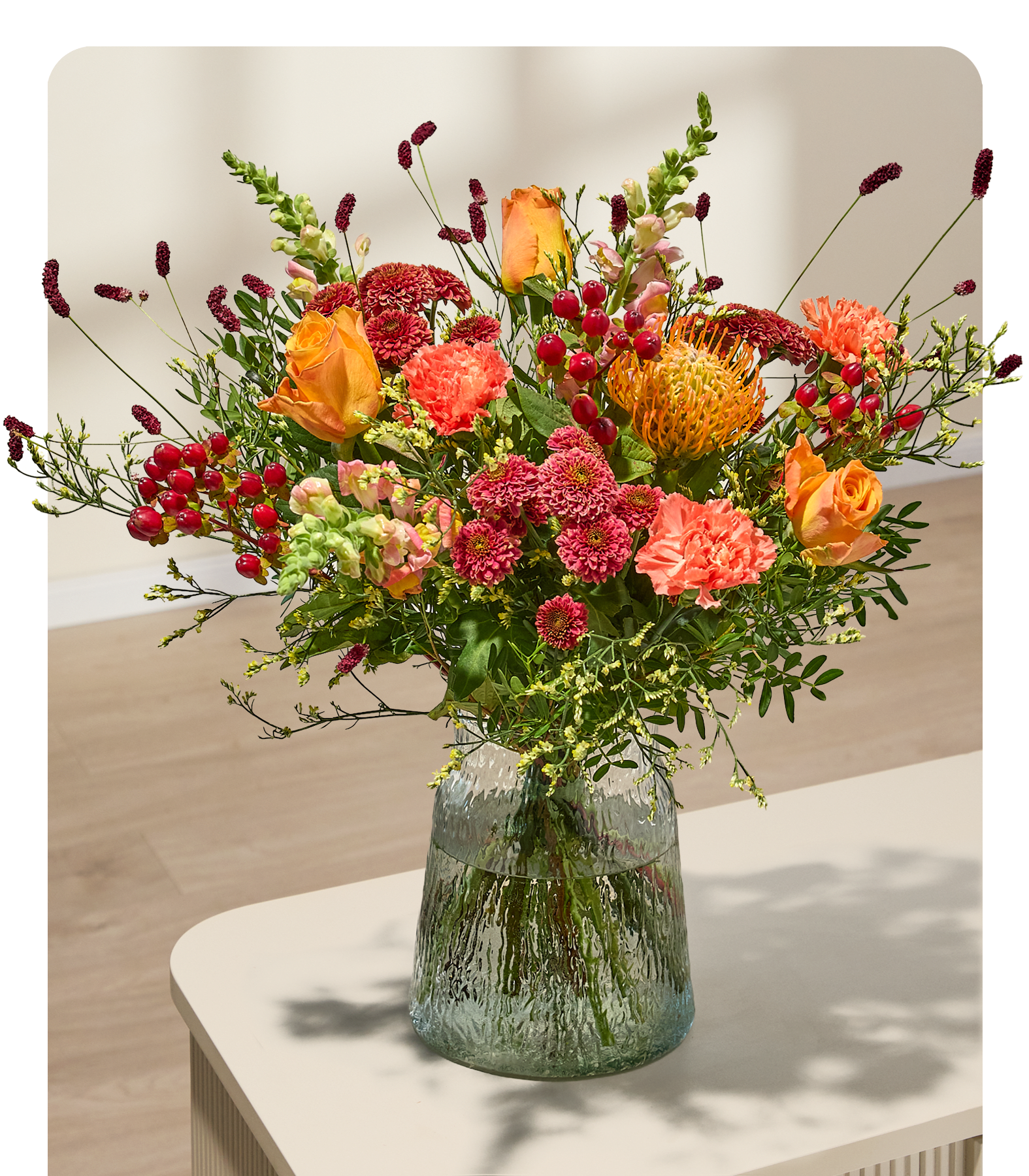 Eine Person in einem weinroten Hemd und Jeans hält einen leuchtenden Strauß orangefarbener und rosafarbener Blumen vor einem schlichten, hellen Hintergrund. (Beschreibungstext KI-generiert)