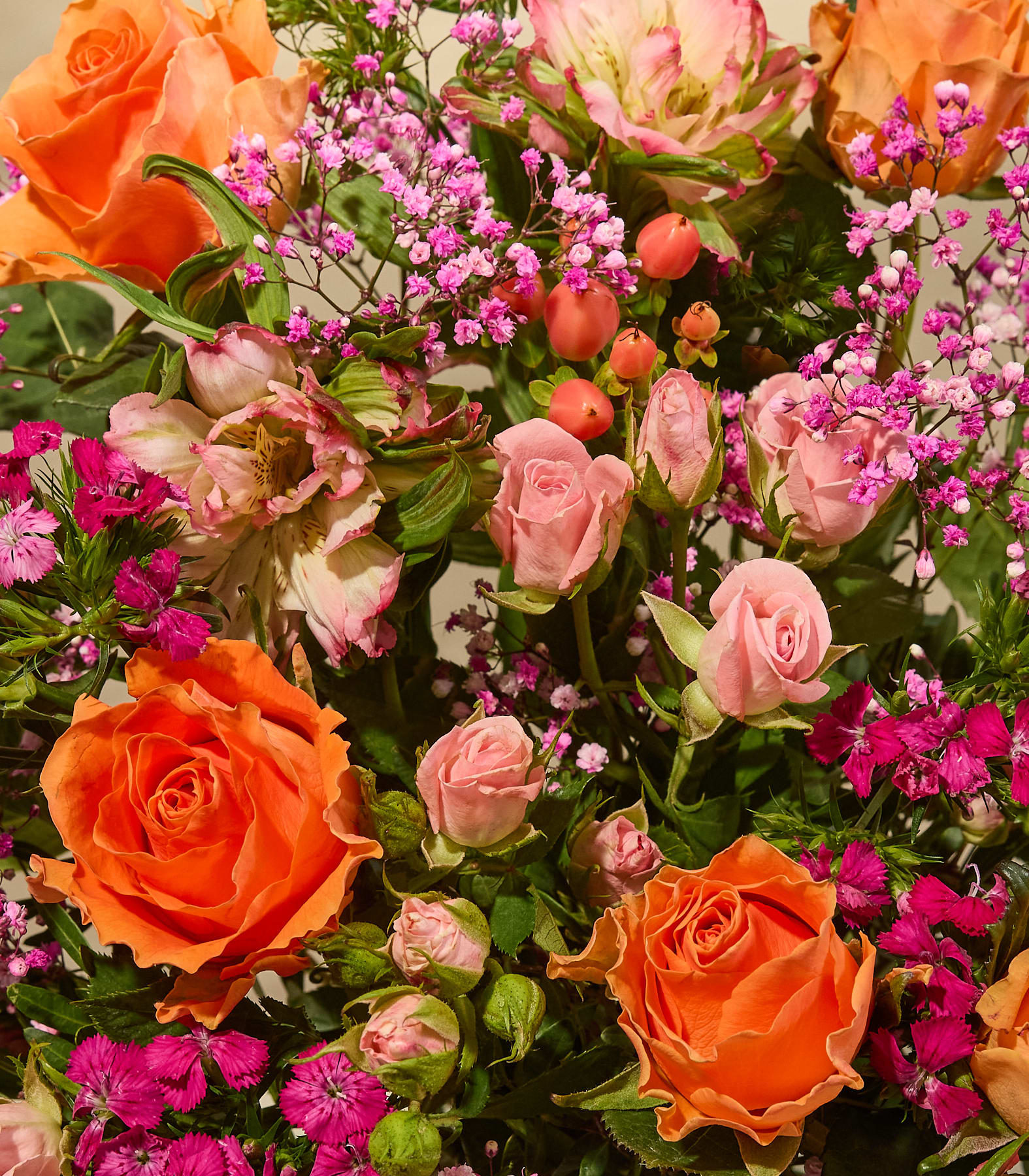 Ein leuchtender Strauß aus orangefarbenen und rosafarbenen Rosen, akzentuiert mit zartem rosa Schleierkraut und fuchsiafarbenen Nelken, füllt das Bild. (Beschreibungstext KI-generiert)
