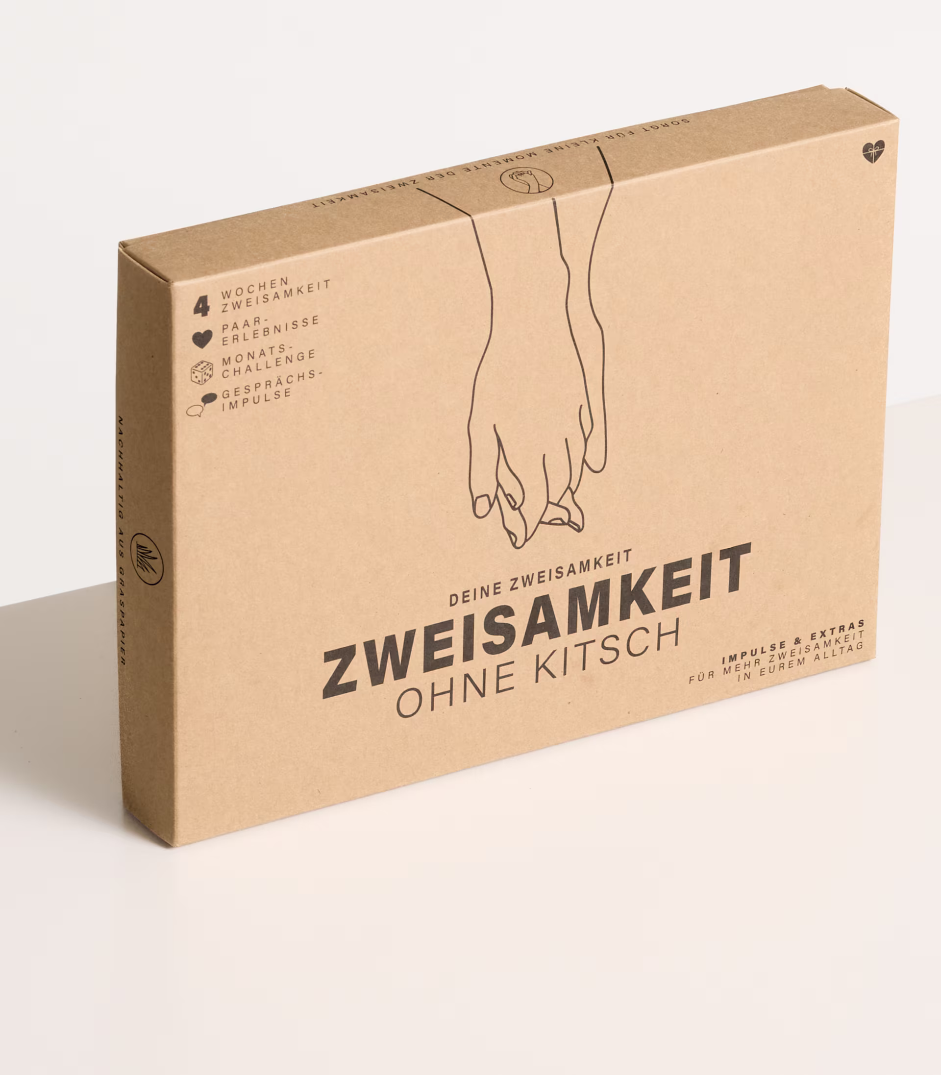 Ein Karton mit dem Aufdruck „Zweisamkeit ohne Kitsch“ auf schlichtem weißem Hintergrund. (Beschreibungstext KI-generiert)
