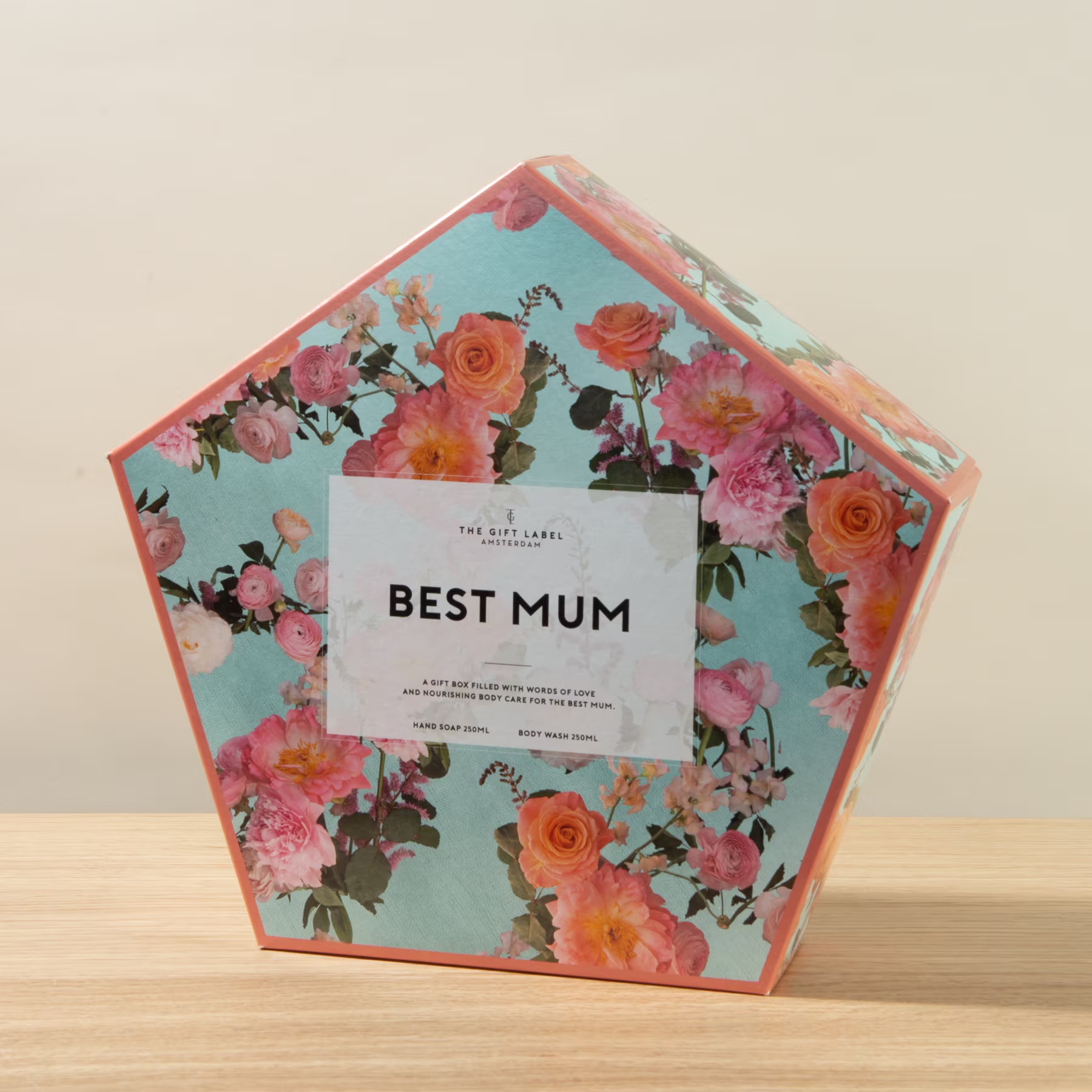 Eine farbenfrohe Geschenkbox mit Blumenmuster und dem deutlich sichtbaren Text „BEST MUM“ auf der Vorderseite. (Beschreibungstext KI-generiert)