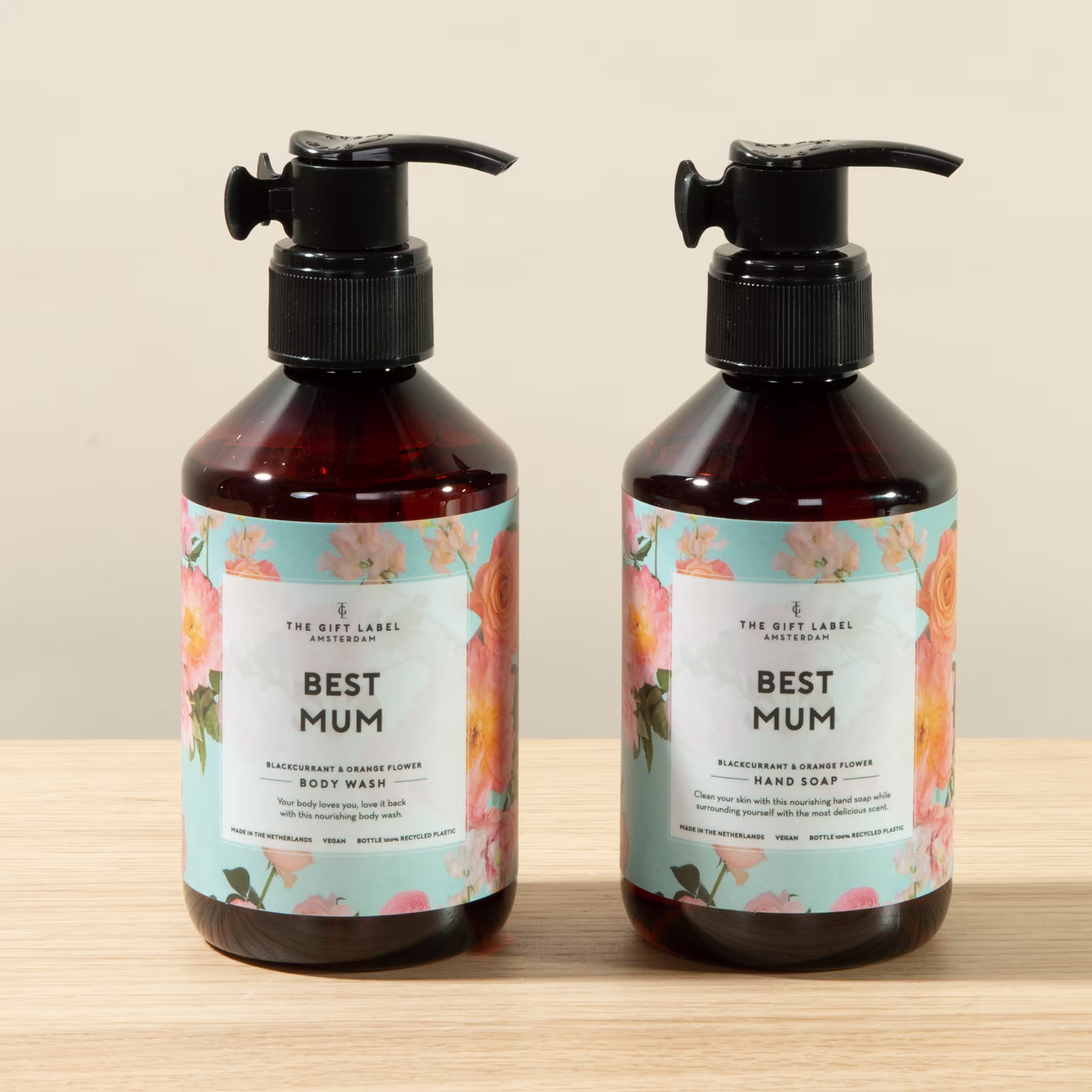 Zwei Flaschen „Best Mum“-Duschgel oder -Lotion mit Blumenmustern auf den Etiketten, die auf einer Holzoberfläche ruhen. (Beschreibungstext KI-generiert)