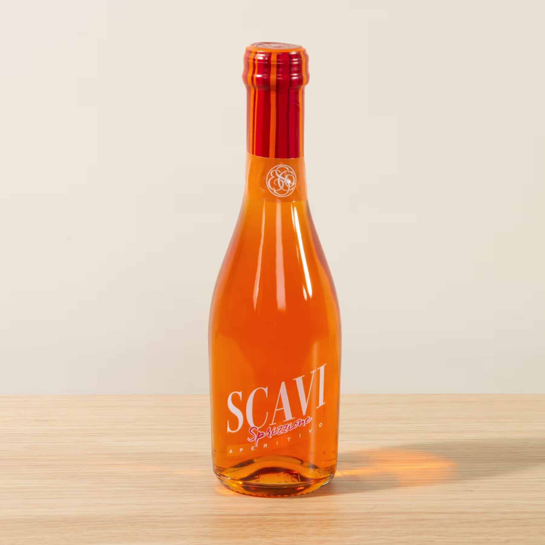 Eine leuchtend orangefarbene Glasflasche mit dem auffälligen Etikett „SCAVI“ steht auf einer Holzoberfläche vor einem schlichten Hintergrund. (Beschreibungstext KI-generiert)