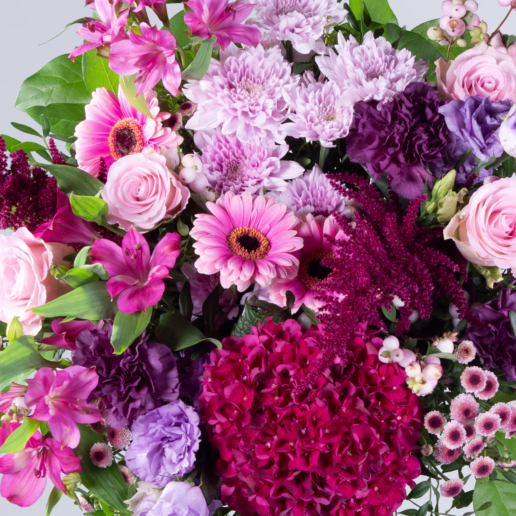Ein lebendiger Strauß verschiedener rosa, violetter und roter Blumen, darunter Rosen, Gerbera und Chrysanthemen, vor einem hellen Hintergrund. (Beschreibungstext KI-generiert)