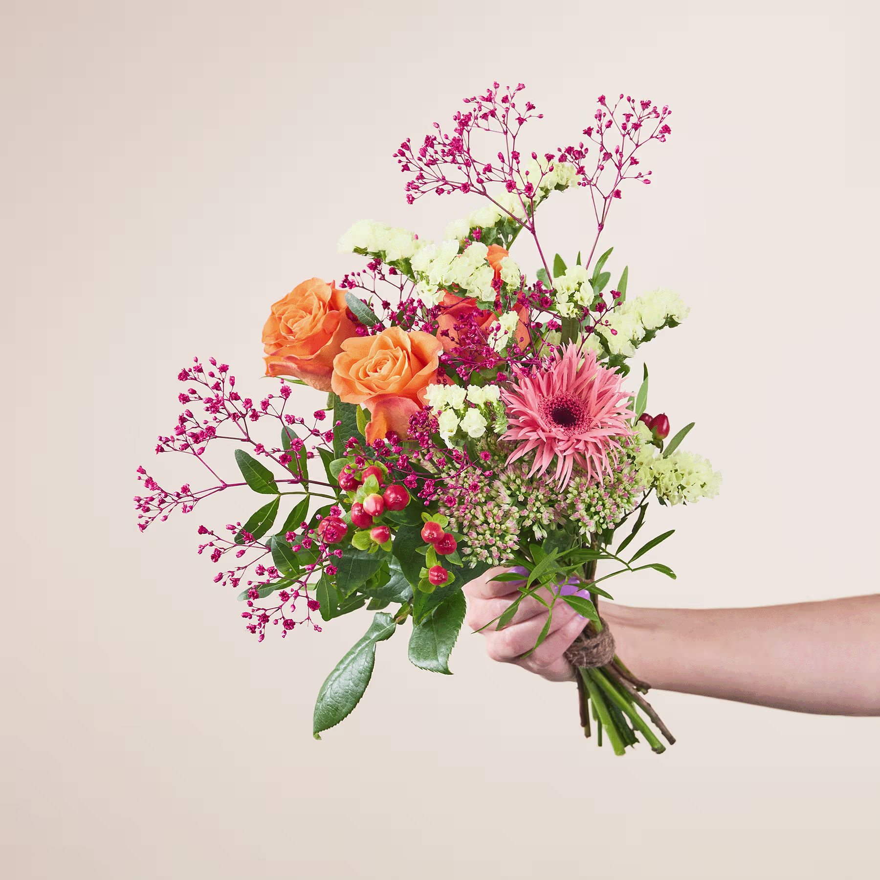 Ein lebendiger Strauß bunter Blumen, darunter orangefarbene Rosen, rosa Gerbera und verschiedene Grünpflanzen, wird vor einem schlichten Hintergrund in den Händen einer Person gehalten. (Beschreibungstext KI-generiert)