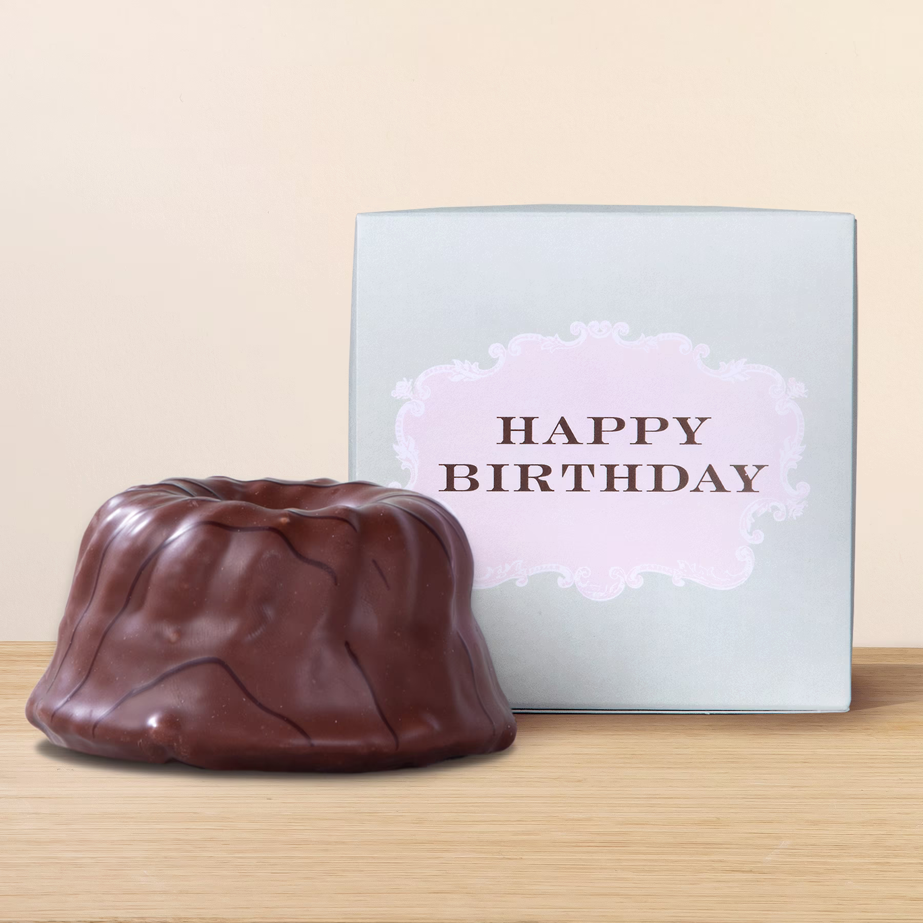 Ein Schokoladenkuchen mit einer „Happy Birthday“-Karte auf einer Holzoberfläche. (Beschreibungstext KI-generiert)