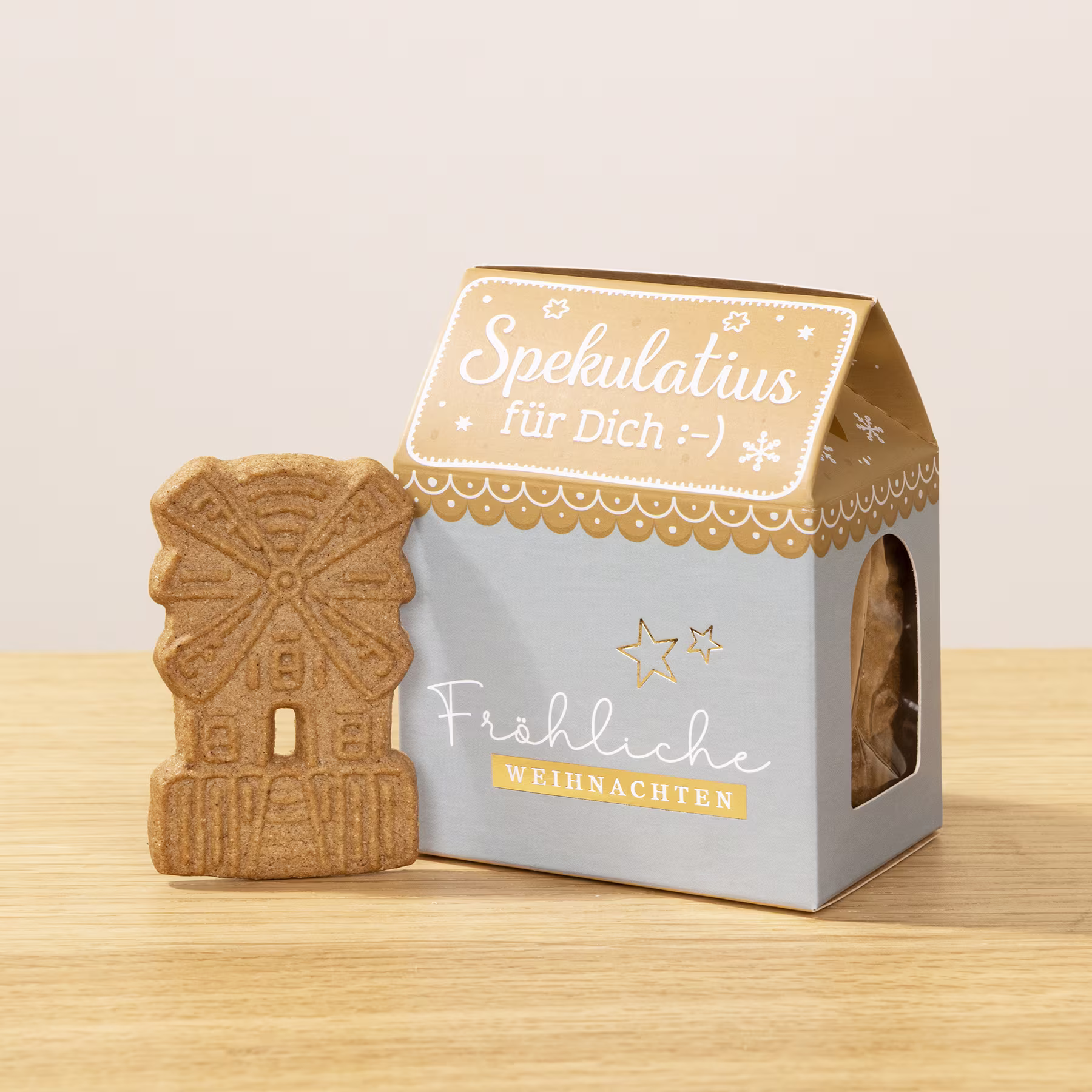 Eine kleine, dekorative Schachtel mit dem Text „Spekulatius für dich“ und einem Lebkuchen in Windmühlenform auf Holzuntergrund. (Beschreibungstext KI-generiert)