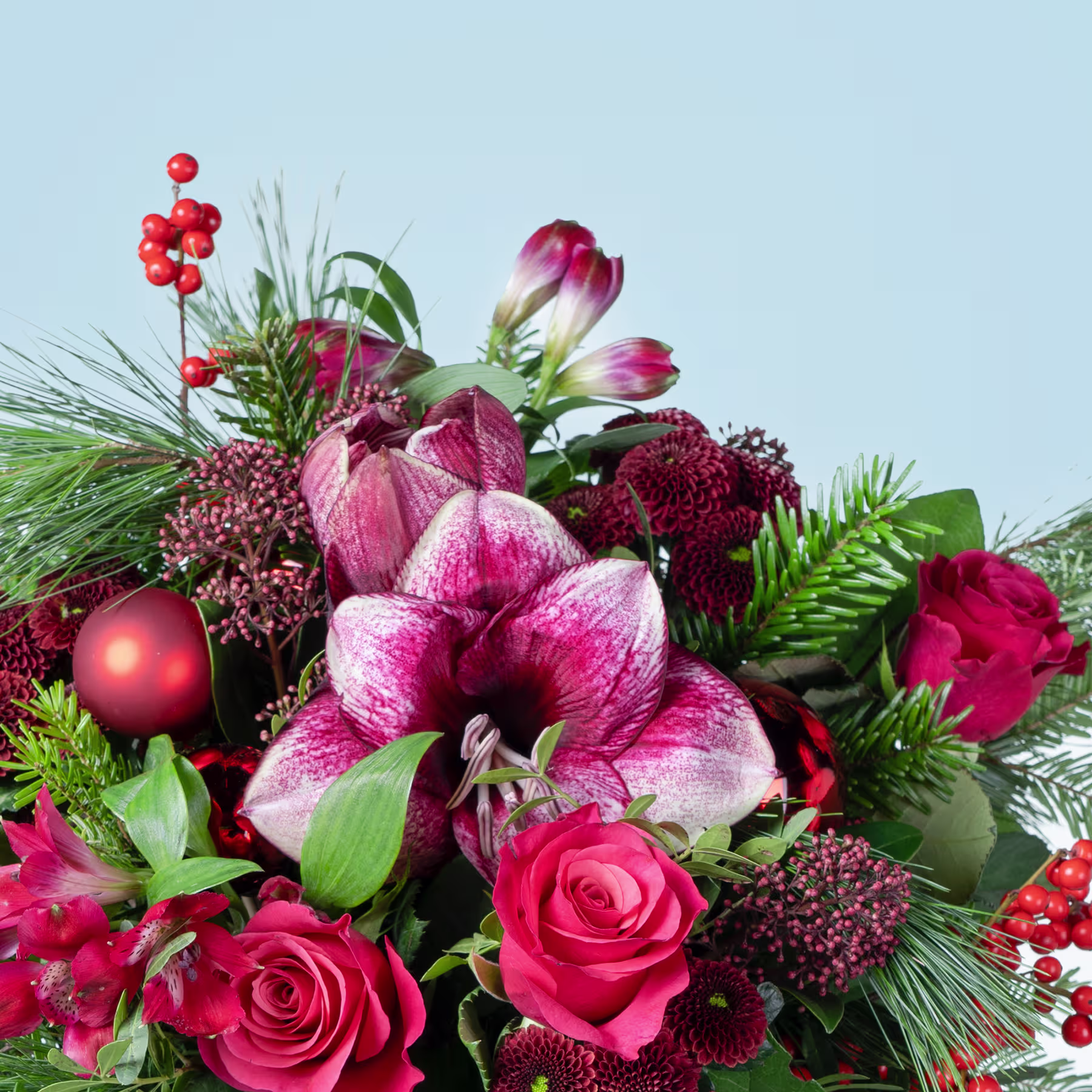 Ein leuchtender Strauß roter und rosa Blumen, darunter Rosen, Lilien und andere Blüten, vor dem Hintergrund eines klaren blauen Himmels. (Beschreibungstext KI-generiert)
