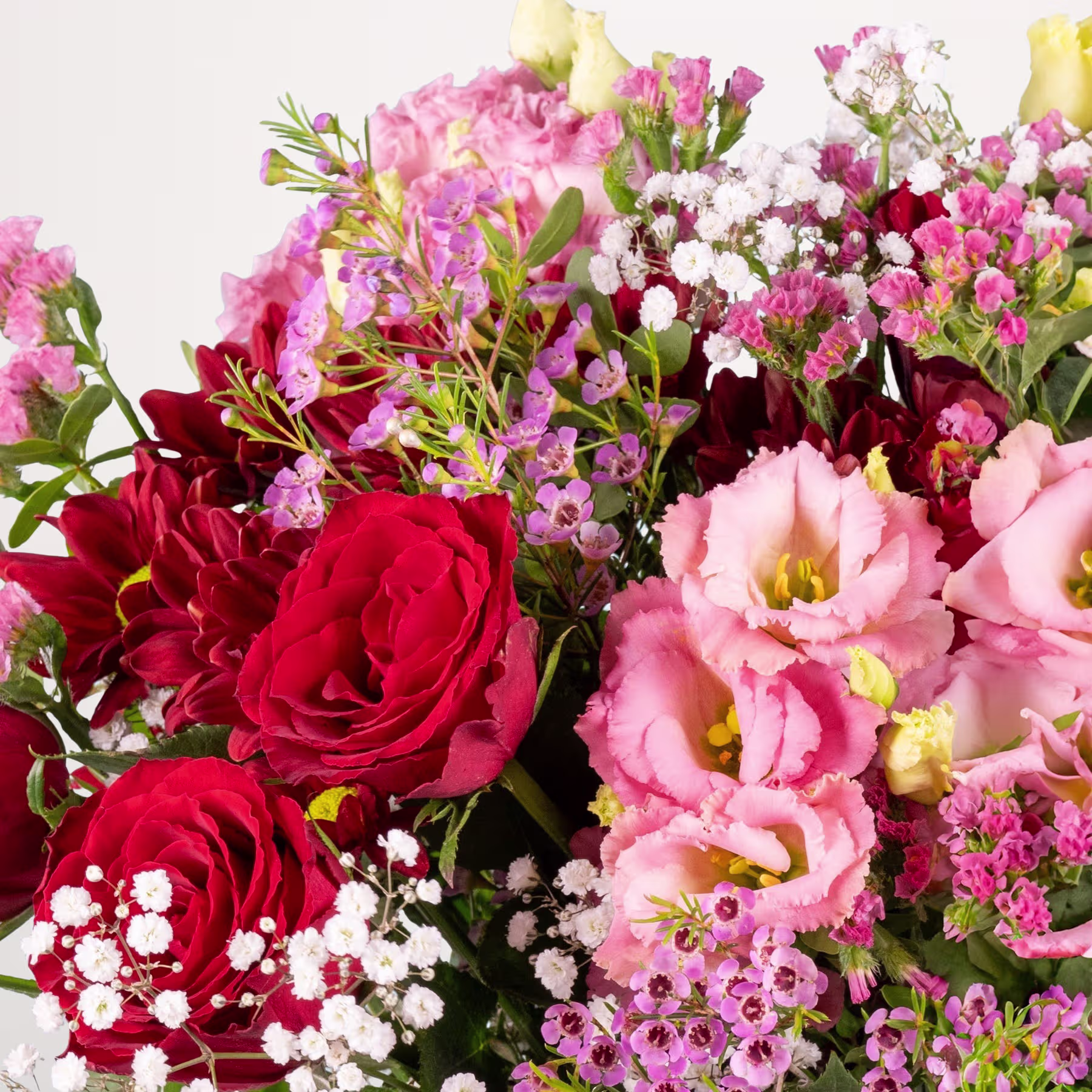 Ein lebendiger Strauß roter Rosen, rosa Nelken und anderer bunter Blumen vor einem schlichten weißen Hintergrund. (Beschreibungstext KI-generiert)