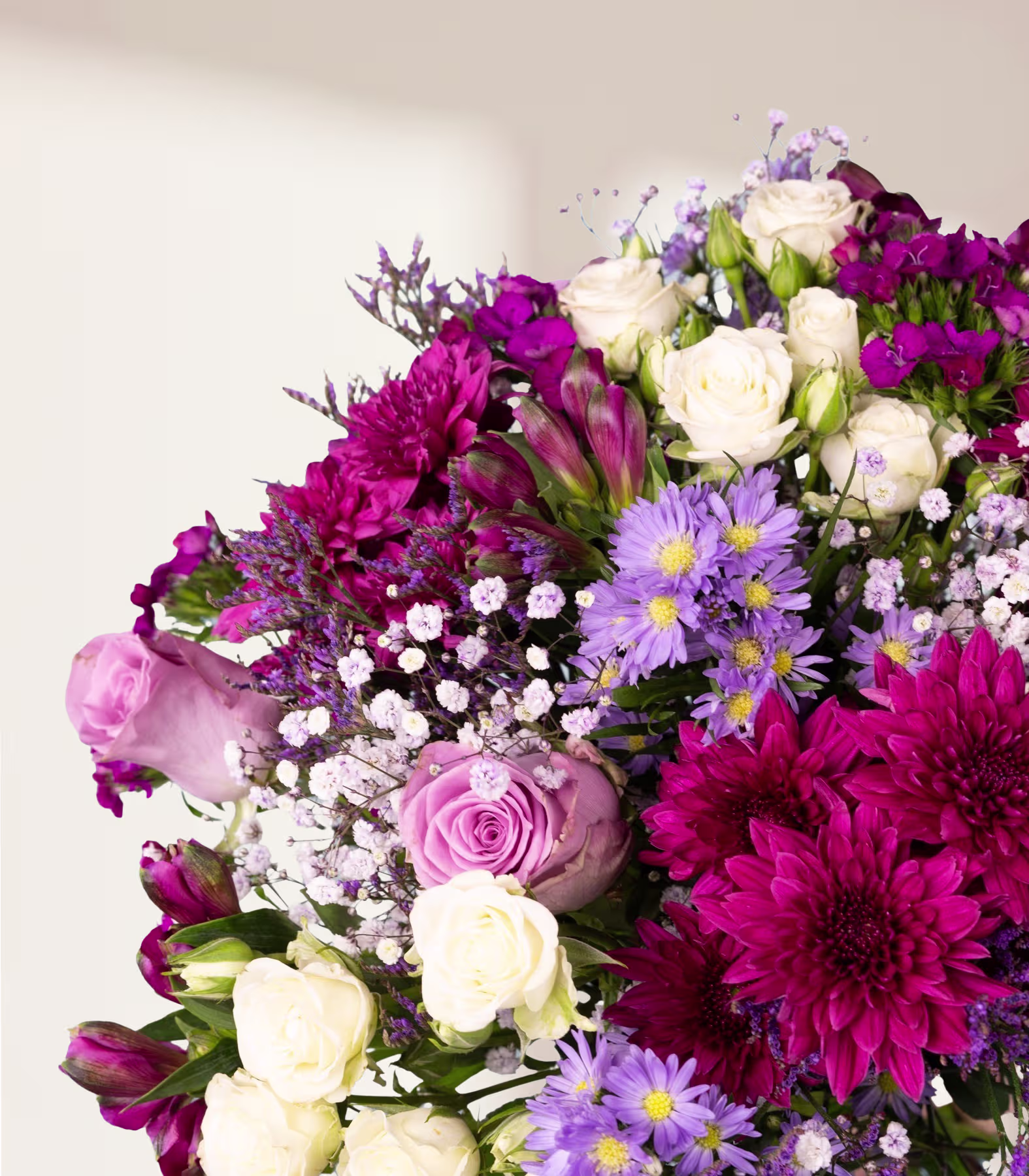 Ein farbenfroher Strauß verschiedener Blumen, darunter rosa Rosen, violette und weiße Gänseblümchen und dunkelrote Dahlien, arrangiert vor einem schlichten weißen Hintergrund. (Beschreibungstext KI-generiert)
