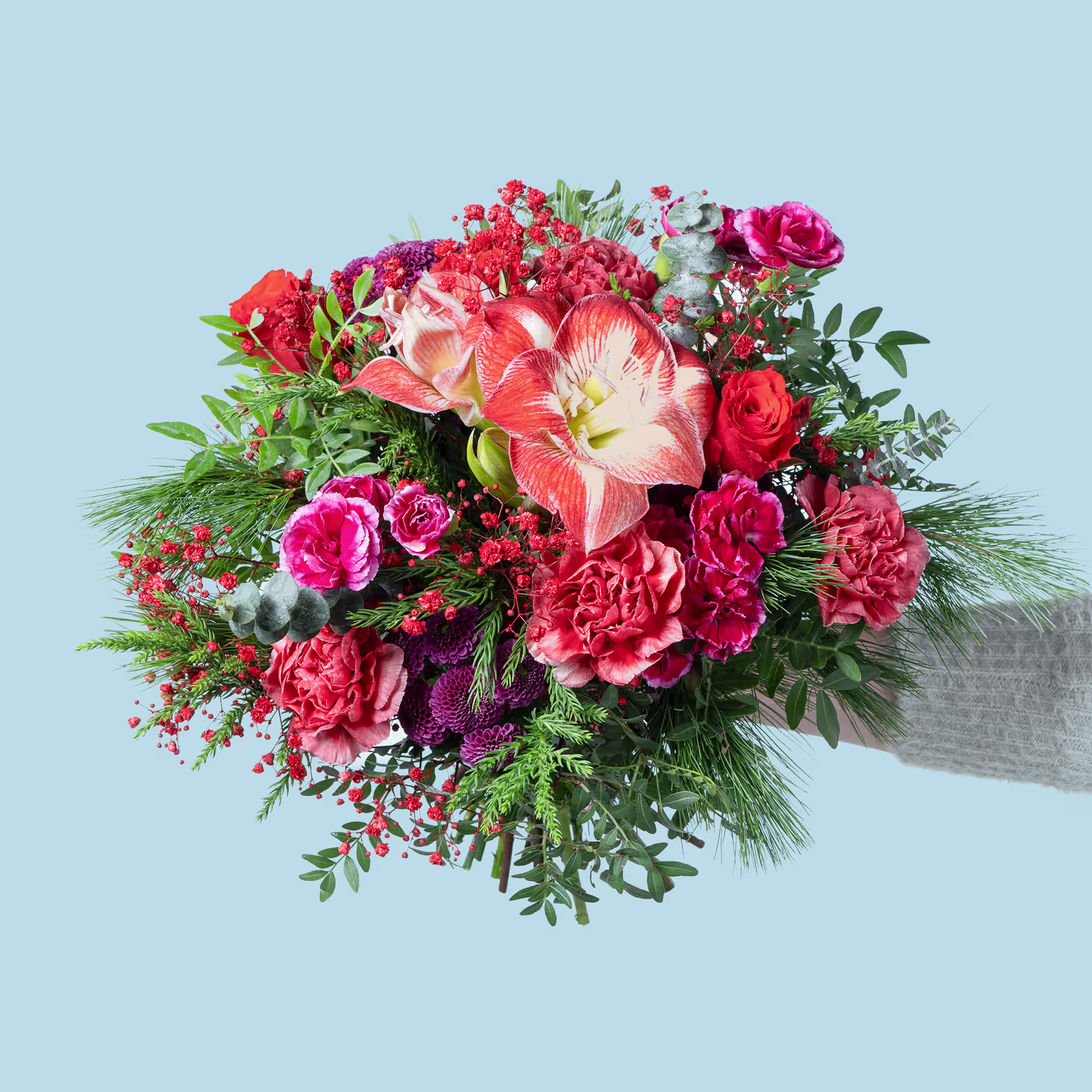 Ein leuchtender Strauß roter, rosa und orangefarbener Blumen, darunter Rosen, Nelken und andere Blüten, vor einem hellblauen Hintergrund. (Beschreibungstext KI-generiert)