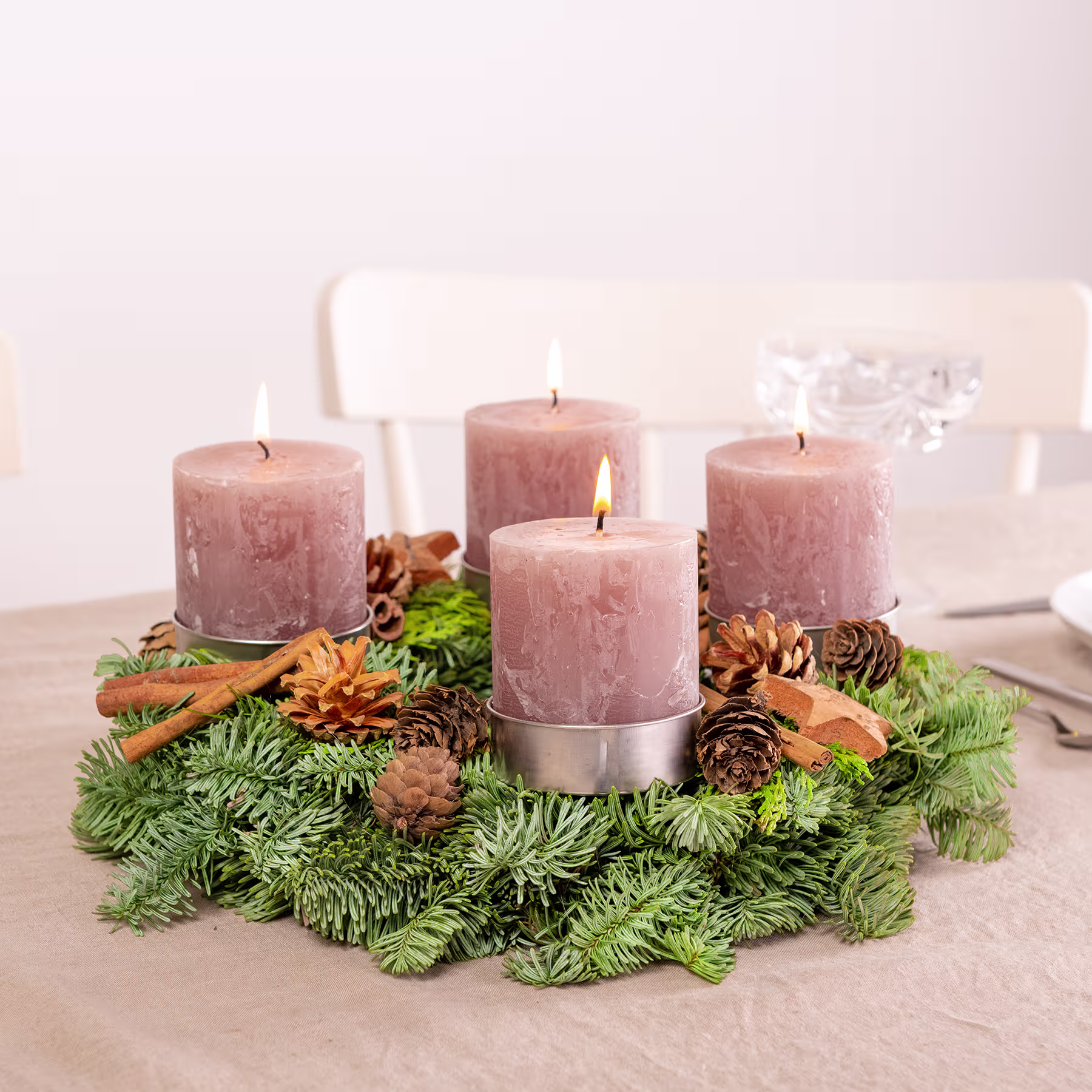 Ein festlicher Weihnachtskranz, geschmückt mit rosa Kerzen, Tannenzapfen und Grünpflanzen, steht auf einer Holzoberfläche vor einem schlichten Hintergrund. (Beschreibungstext KI-generiert)