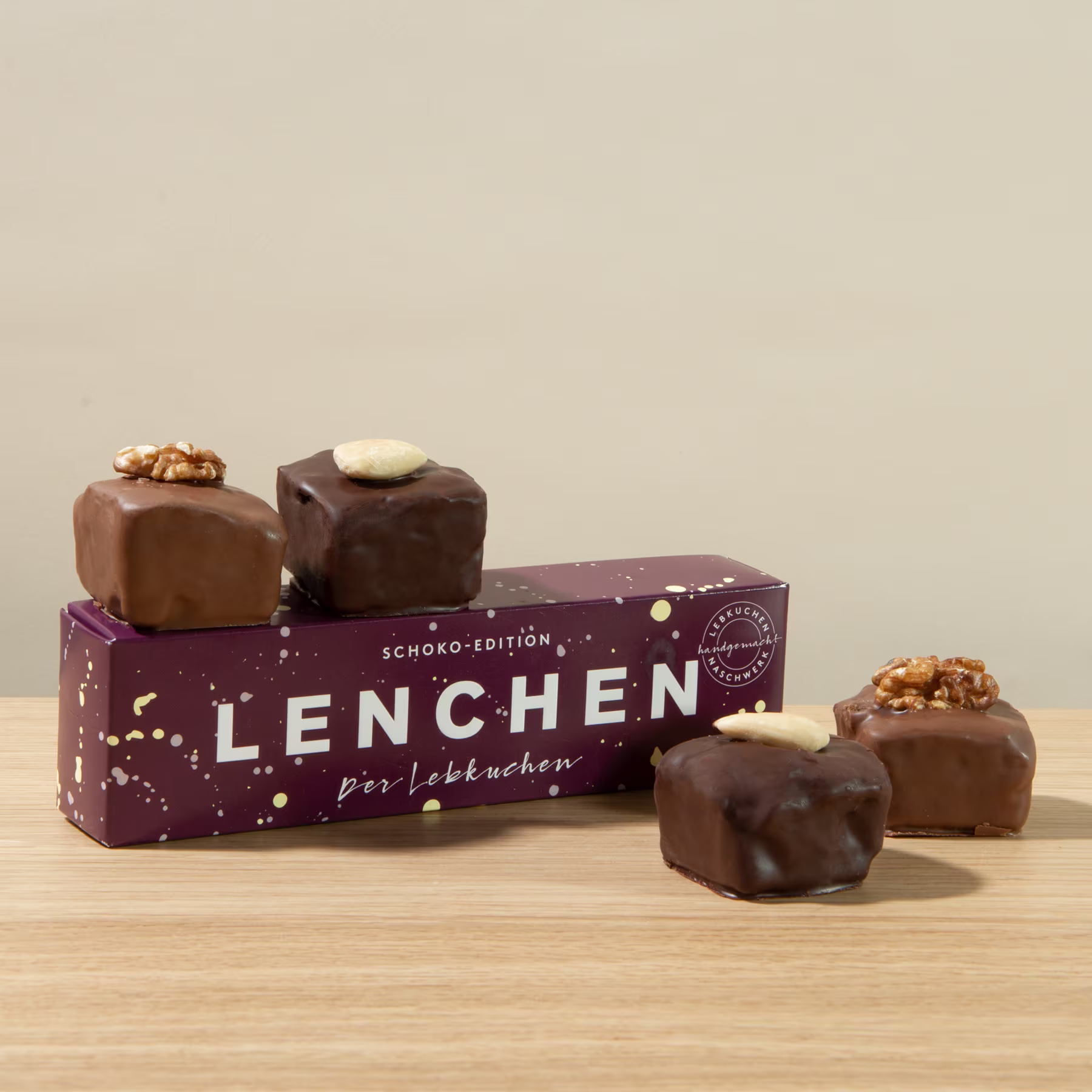 Das Bild zeigt eine Pralinenschachtel namens „Lenchen“ mit mehreren schokoladenüberzogenen Pralinen im Vordergrund, die auf einer Holzoberfläche ruhen. (Beschreibungstext KI-generiert)