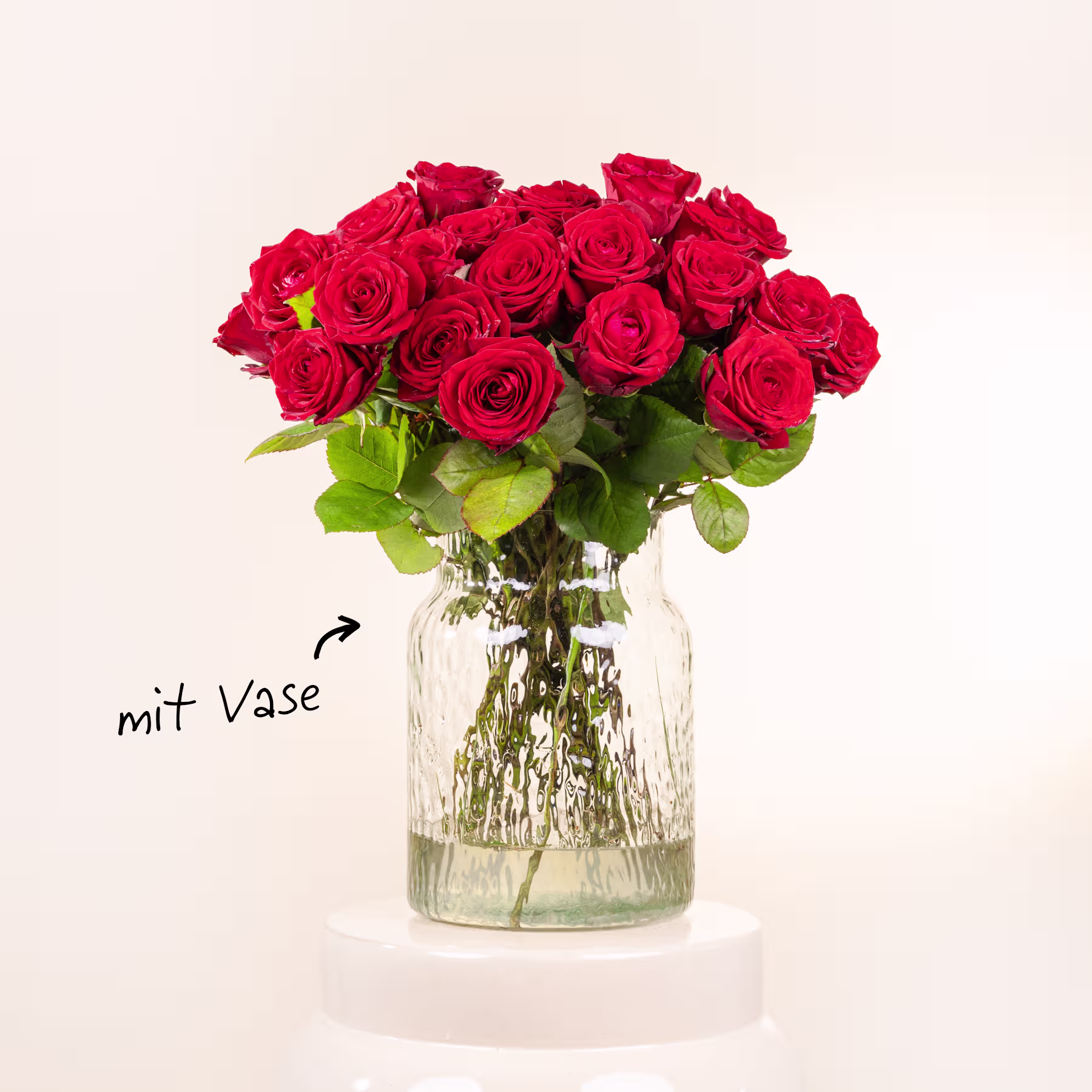 Ein Strauß leuchtend roter Rosen wird in einer Glasvase vor einem schlichten weißen Hintergrund präsentiert. (Beschreibungstext KI-generiert)