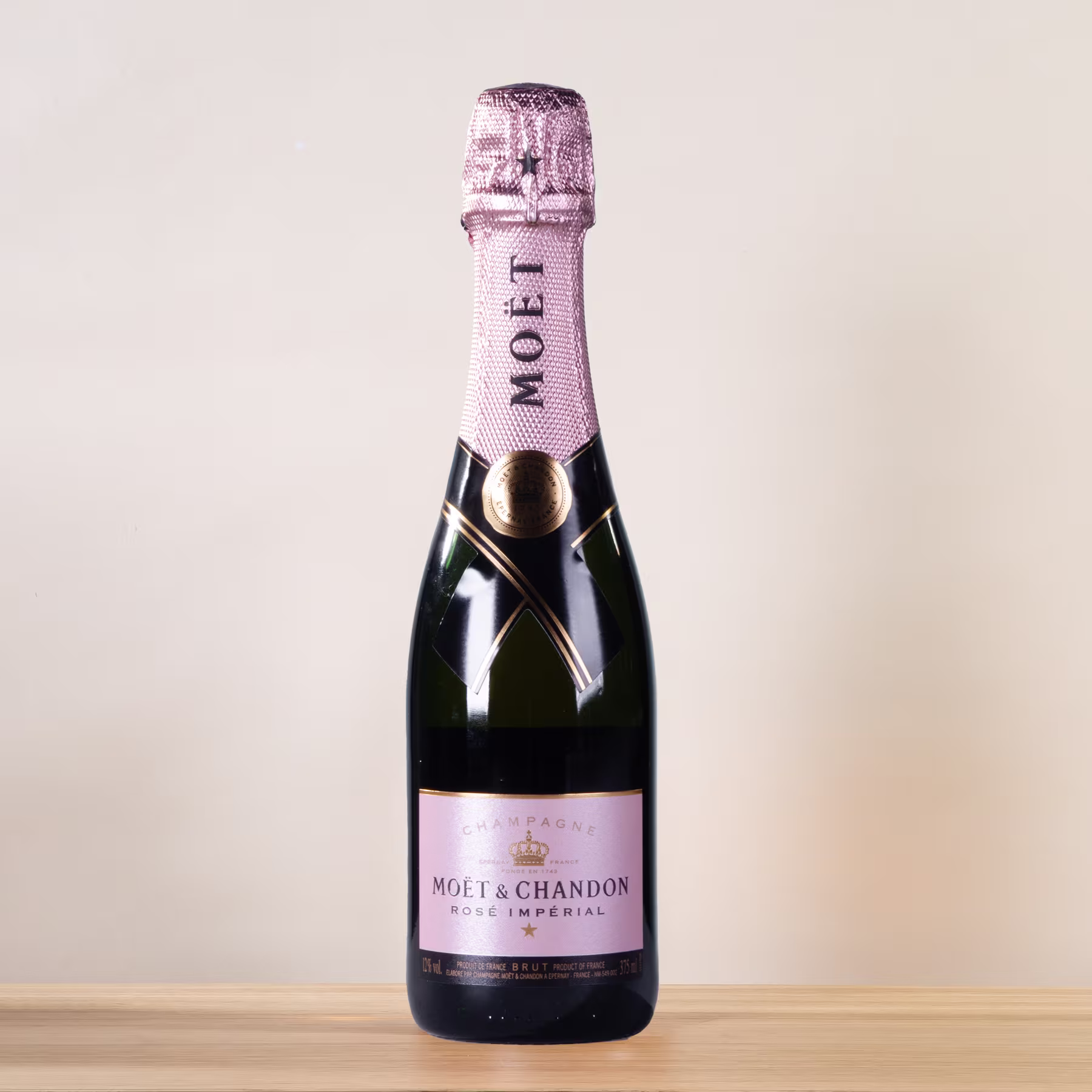 Eine Flasche Champagner von Moët & Chandon steht auf einer Holzoberfläche vor einem schlichten, hellen Hintergrund. (Beschreibungstext KI-generiert)