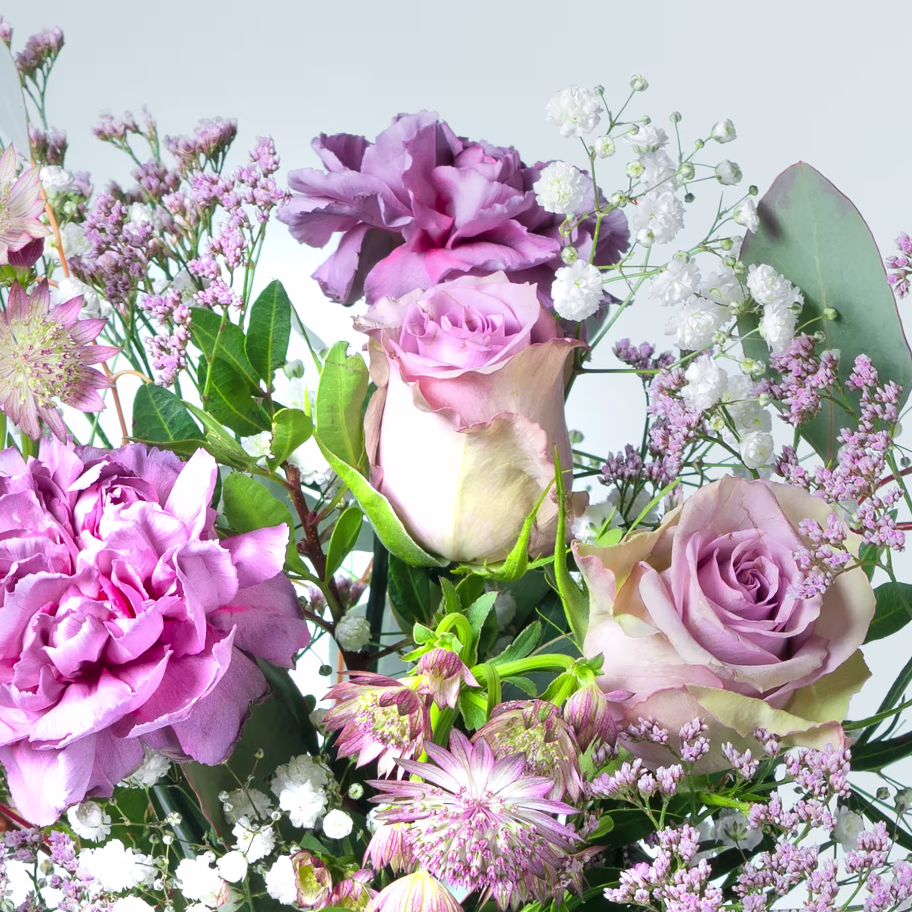 Ein lebendiger Strauß rosa und violetter Blumen, darunter Rosen, Pfingstrosen und andere zarte Blüten, vor einem weichen, unscharfen Hintergrund. (Beschreibungstext KI-generiert)