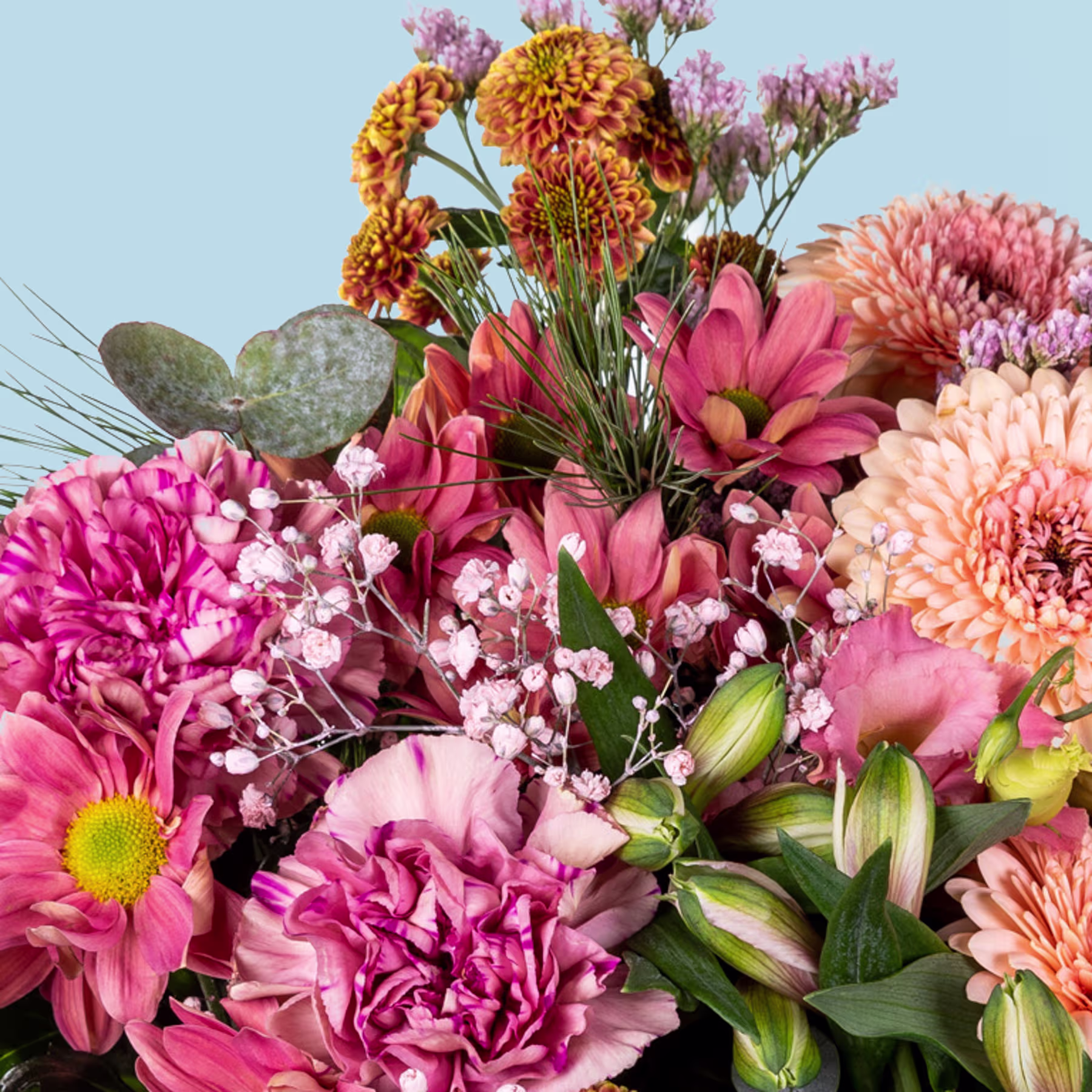 Ein lebendiger Strauß bunter Blumen, darunter rosa Nelken, orangefarbene Chrysanthemen und violette Dahlien, vor einem sanften blauen Hintergrund. (Beschreibungstext KI-generiert)
