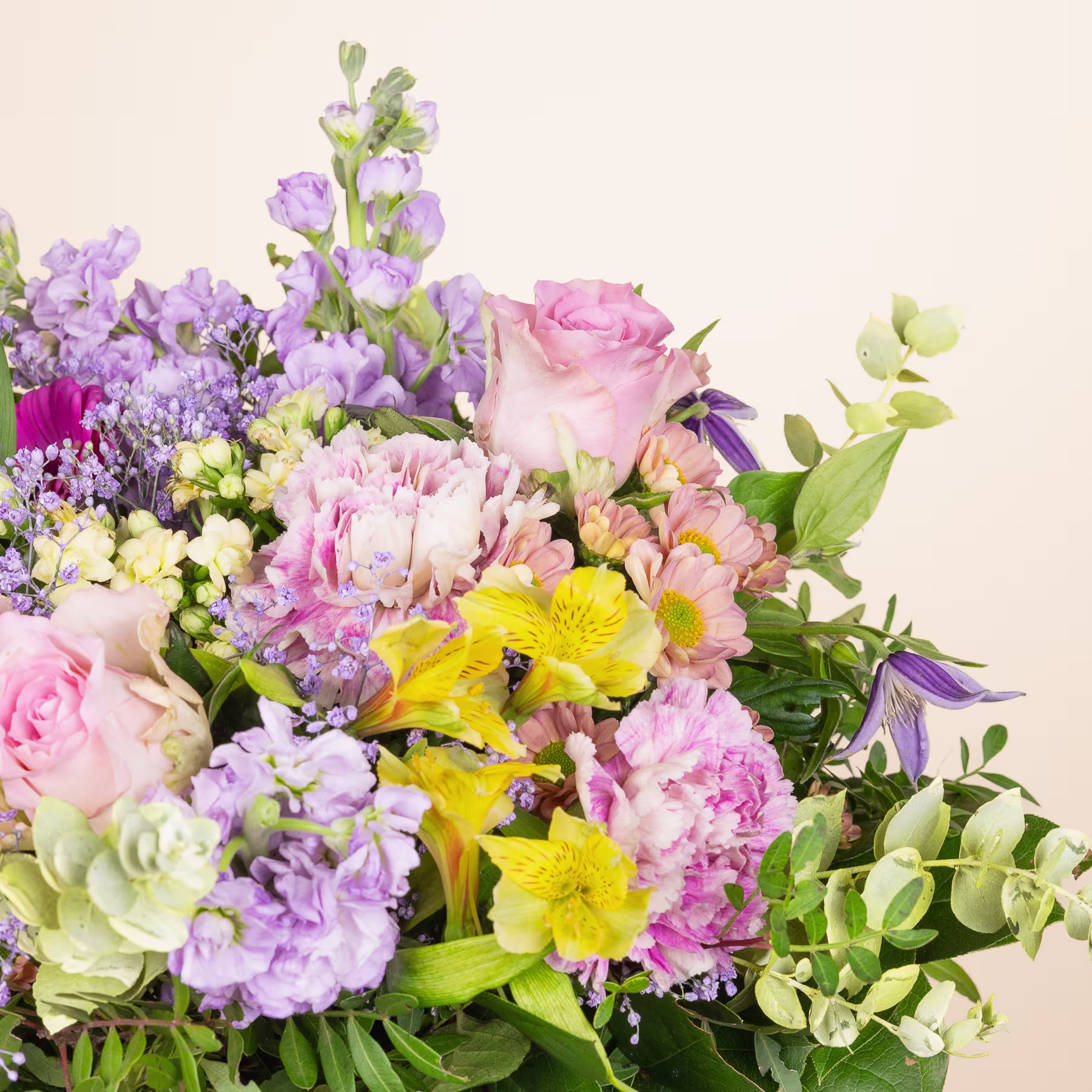 Ein lebendiger Strauß verschiedener bunter Blumen, darunter rosa Rosen, gelbe Narzissen und violette Nelken, vor einem schlichten, hellen Hintergrund. (Beschreibungstext KI-generiert)