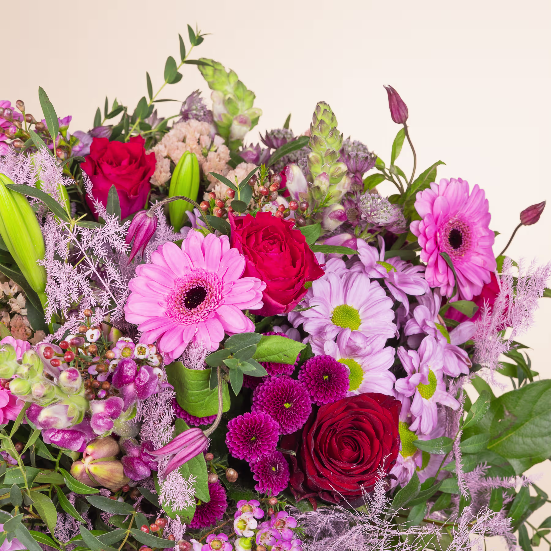 Ein lebendiger Strauß verschiedener bunter Blumen, darunter rote Rosen, rosa Gerbera und lila Chrysanthemen, vor einem hellen Hintergrund. (Beschreibungstext KI-generiert)