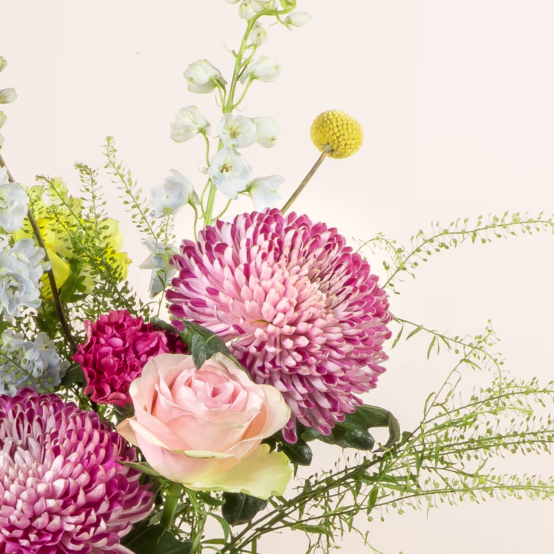 Ein lebendiger Strauß aus rosa Chrysanthemen, pfirsichfarbenen Rosen und gelben Knopfblumen vor einem weichen, neutralen Hintergrund. (Beschreibungstext KI-generiert)