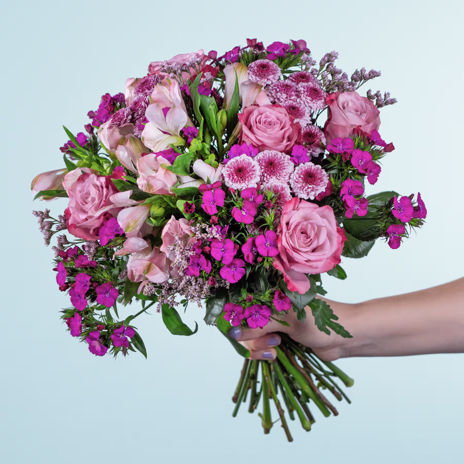 Ein leuchtender Strauß rosa und violetter Blumen, darunter Rosen, Gänseblümchen und andere Blüten, wird vor einem hellblauen Hintergrund in den Händen einer Person gehalten. (Beschreibungstext KI-generiert)