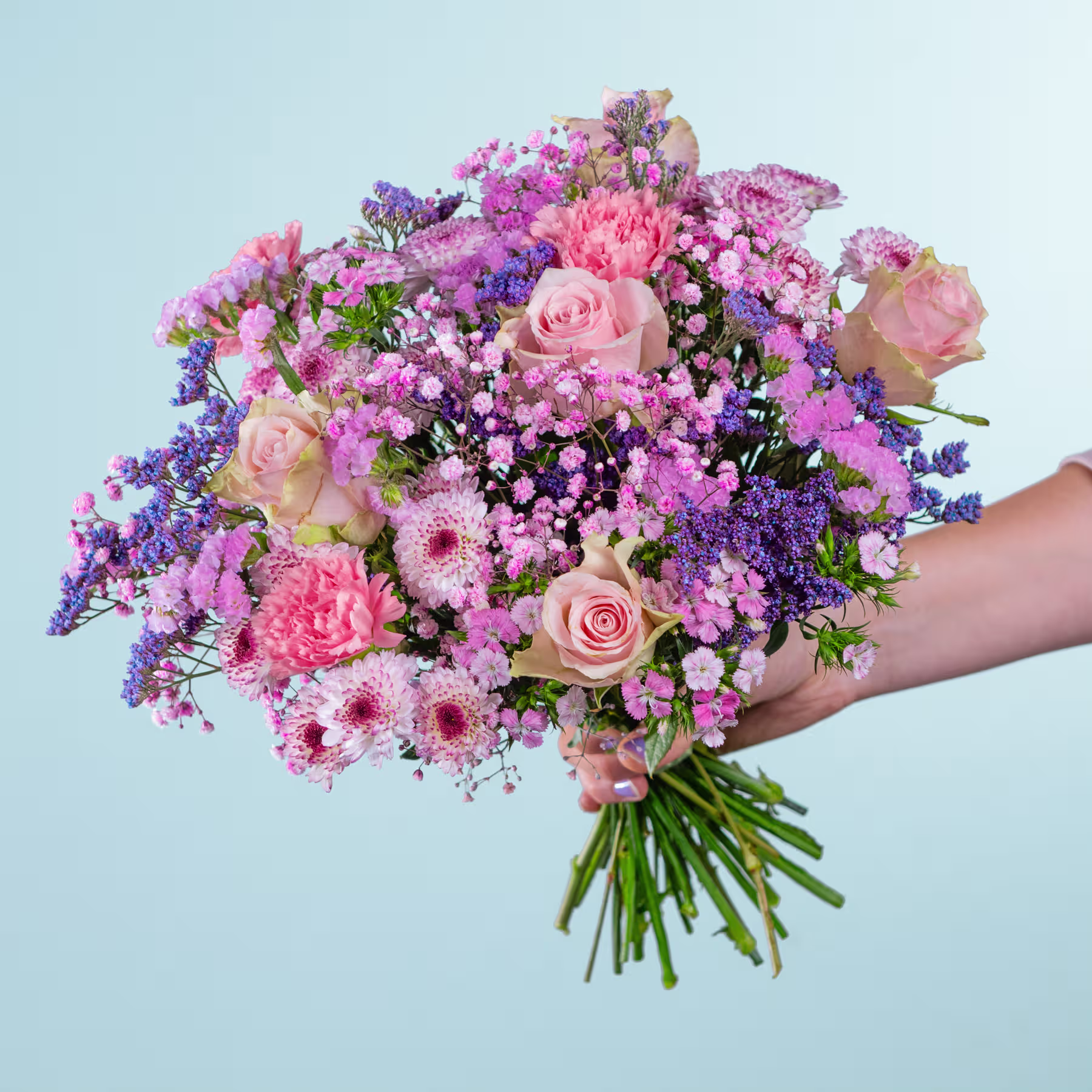 Ein leuchtender Strauß rosa, violetter und weißer Blumen, darunter Rosen und Gänseblümchen, wird vor einem hellblauen Hintergrund in den Händen einer Person gehalten. (Beschreibungstext KI-generiert)